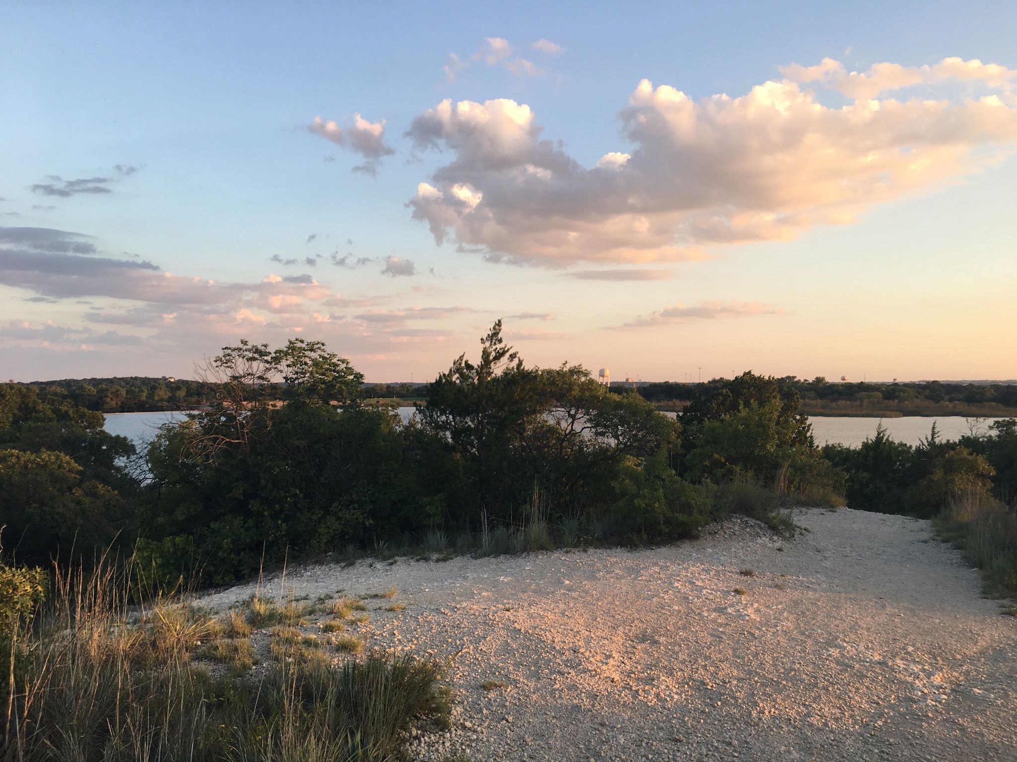 Warm sunset light over a sandy path overlooking a tree-lined lake. - Lone Wolf and The Dam Drop Trail Loop
