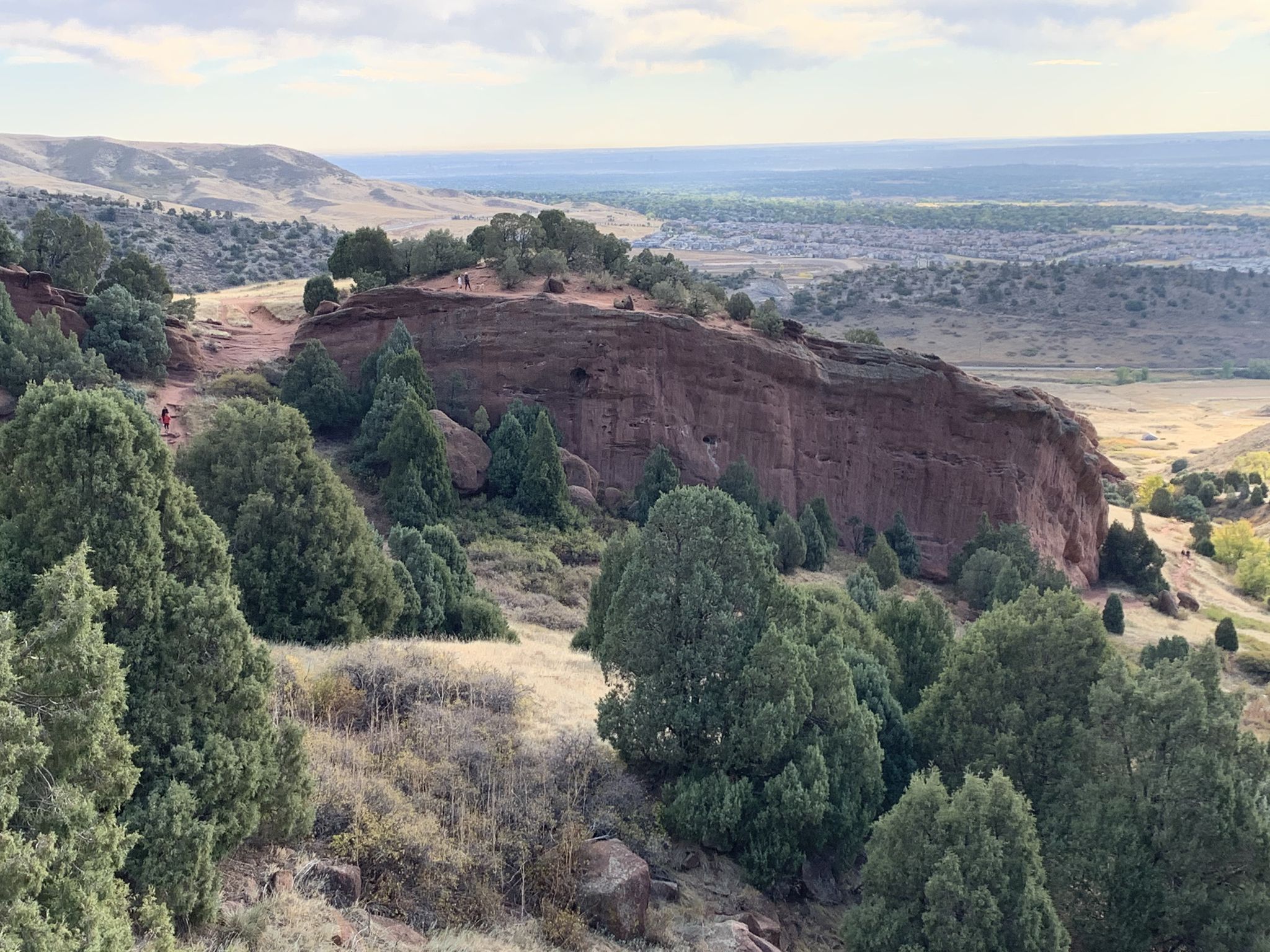 Red rock cliff with scattered trees, overlooking a valley under cloudy sky. - Village Walk, Red Rocks, Cherry Gulch, and Morrison Slide Trail