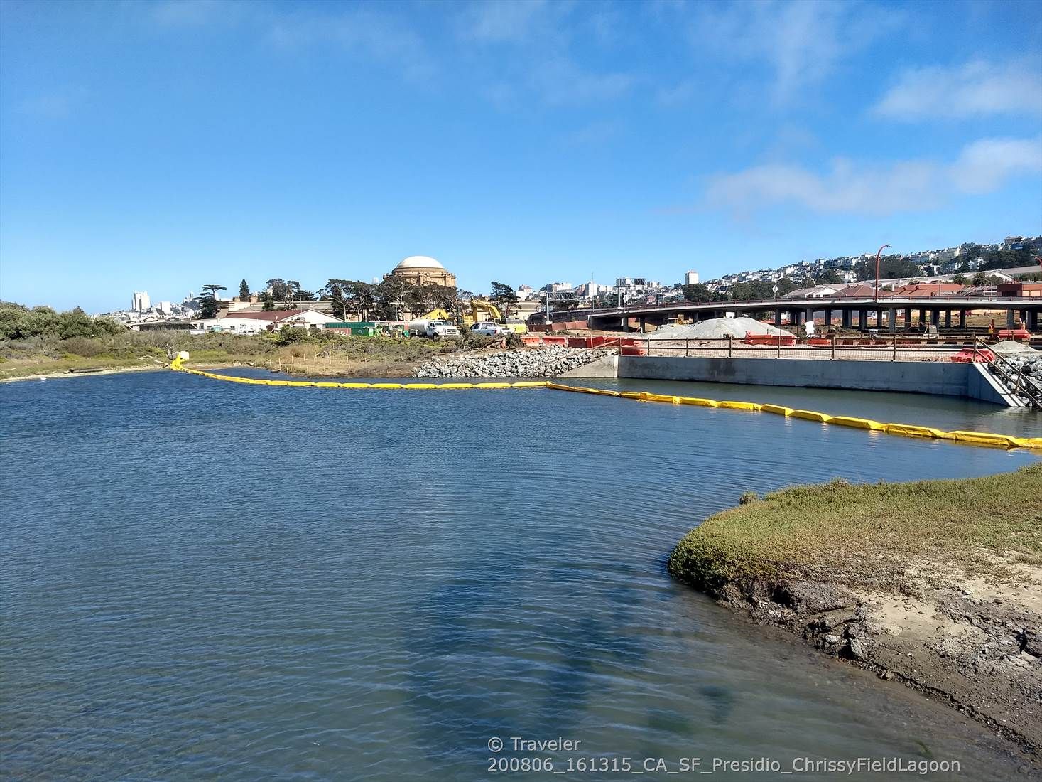 Calm water with a distant city, dome building, and construction under clear sky. - Golden Gate Promenade – Crissy Field beach 🏊 loop from San Francisco Maritime National Historical Park