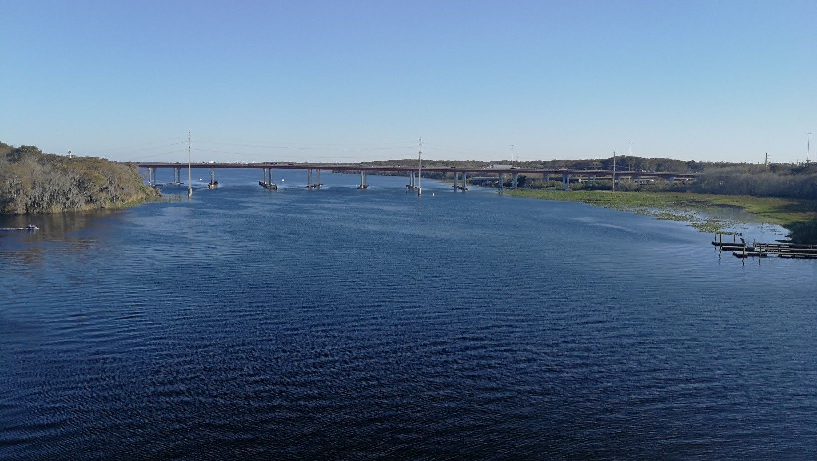 Wide river with distant bridge, boats, and wooded banks under clear sky. - Green Springs Park – Veterans Memorial Park Sanford loop from Orange City - Saxon Lot