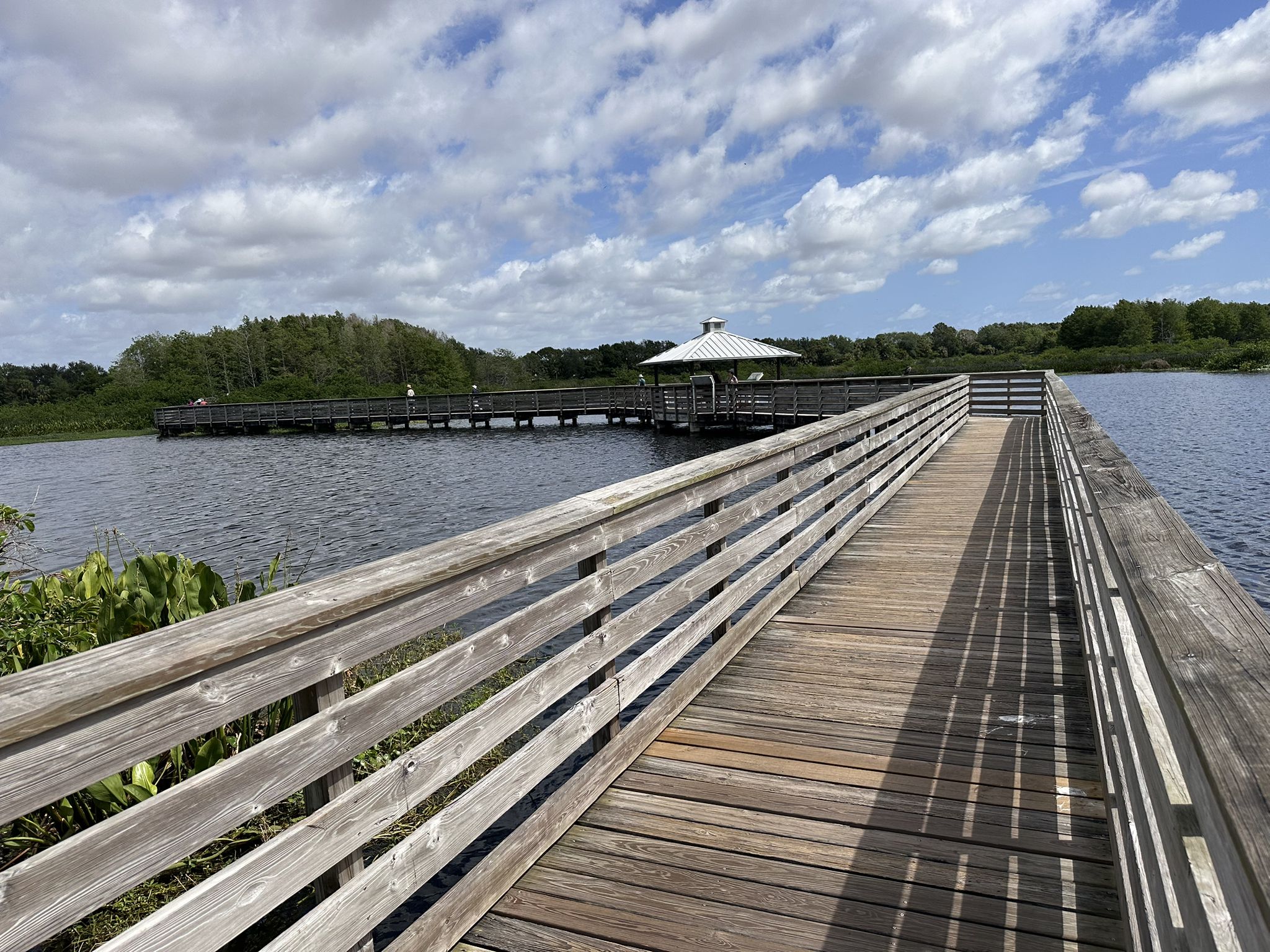 A long wooden boardwalk extends over water towards a distant gazebo. - North Loop