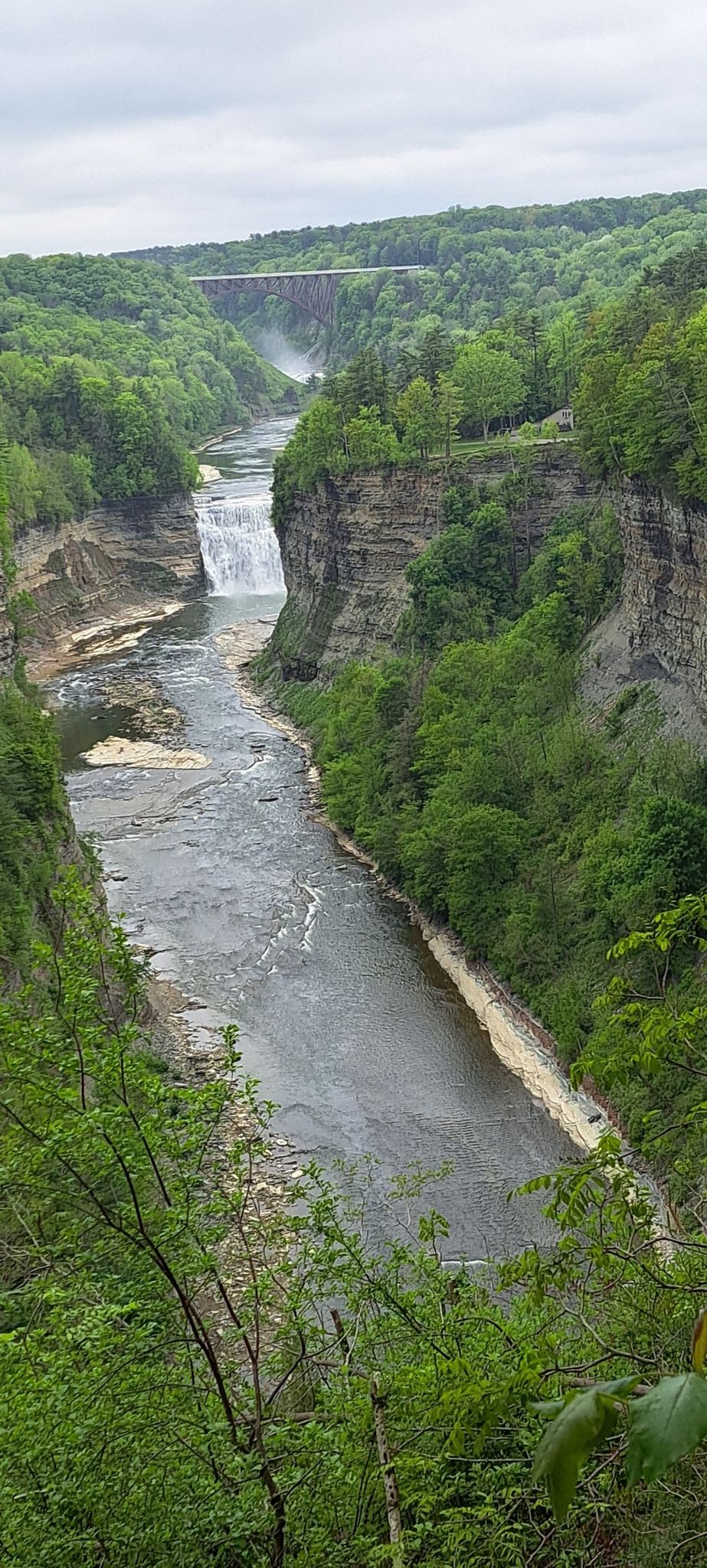 River flowing through a rocky gorge with a waterfall and distant bridge. - Inspiration Point and Lower Falls via Gorge Trail