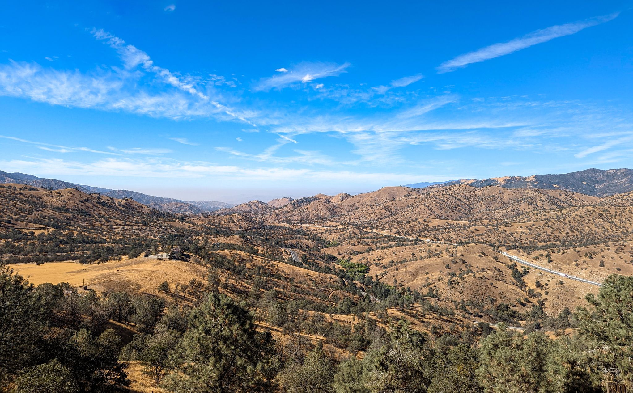 Expansive view of dry, rolling hills and valleys under a bright blue sky. - Bakersfield to Tehachapi loop