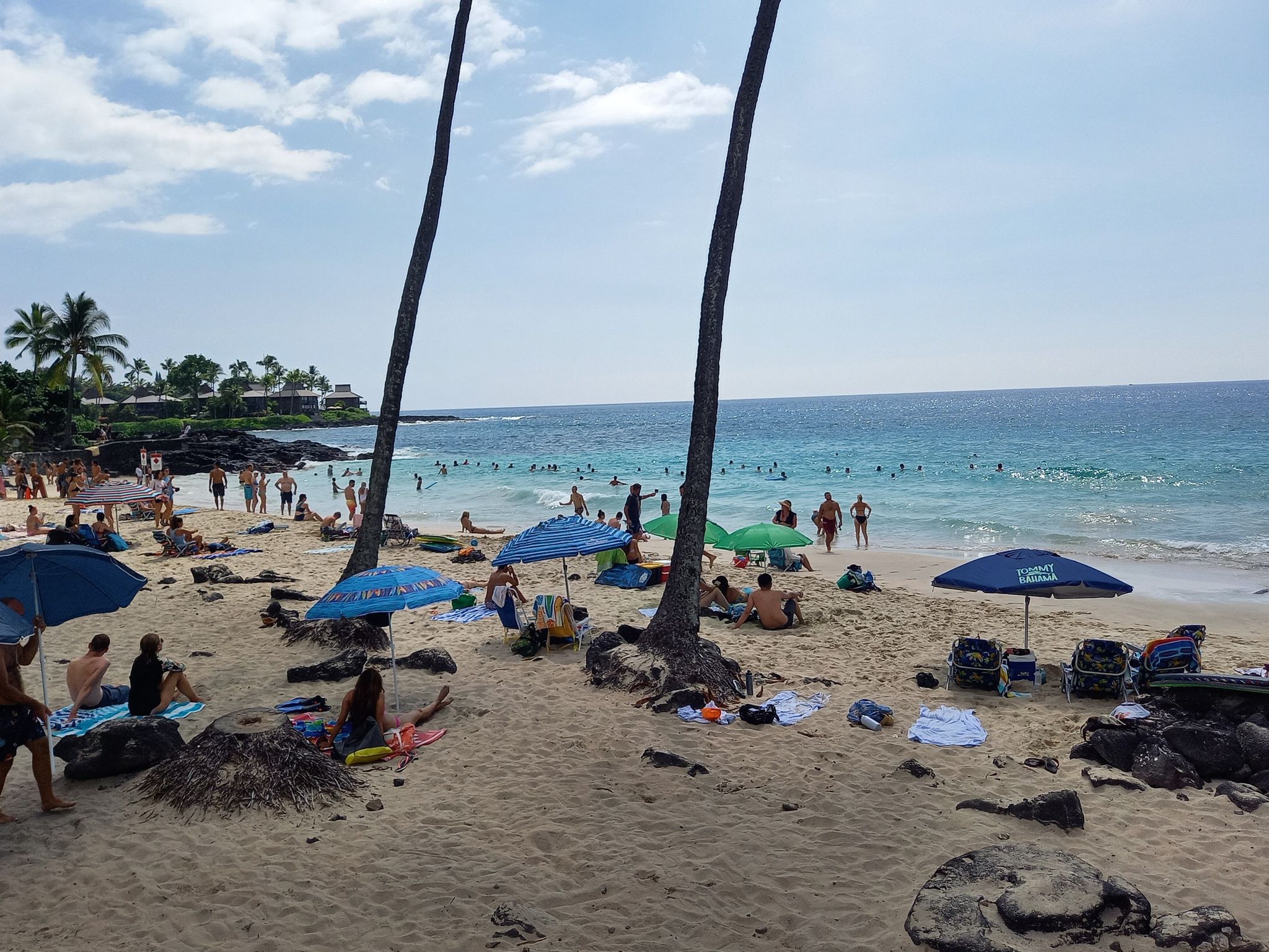 Crowded sandy beach with many people swimming and relaxing under umbrellas. - White Sands Beach Park – Aliʻi Gardens Marketplace loop from White Sands Beach Park