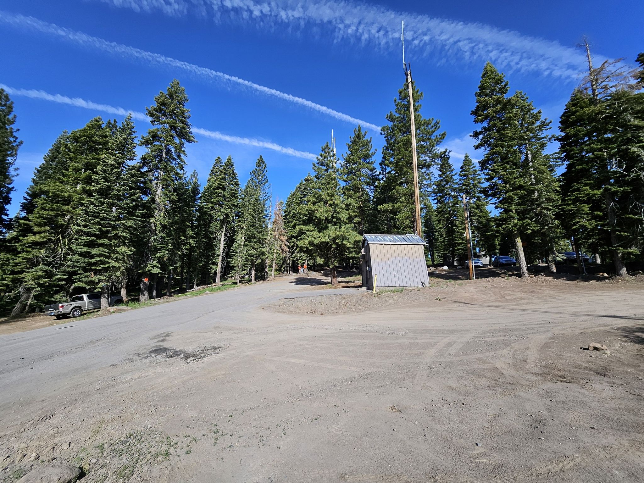 Dirt road intersection with a small shed under a bright blue sky. - Brockway Summit – Watson Lake Campground loop from Tahoe Vista