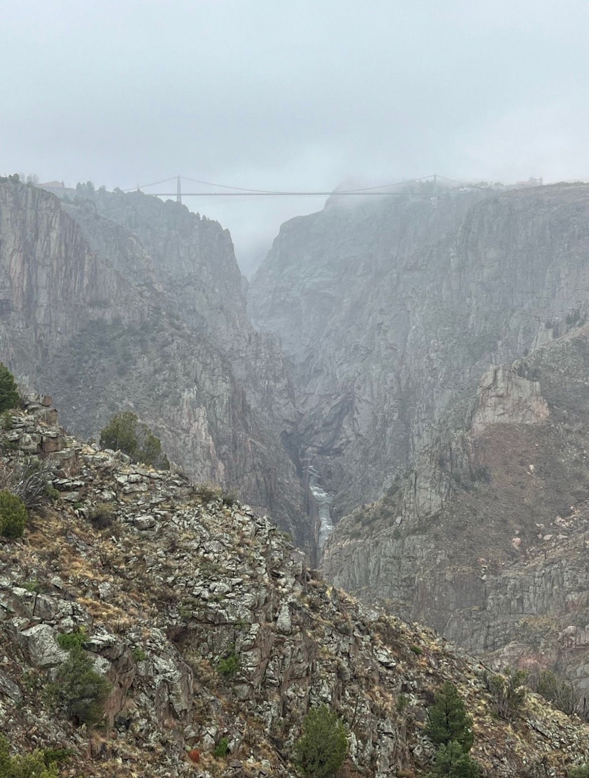 Misty, overcast view of a deep canyon with a bridge in the distance. - Viewpoint – Royal Gorge Bridge loop from Royal Gorge Bridge