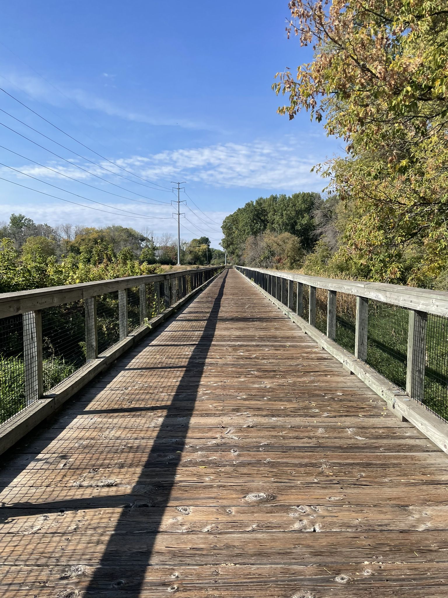 Long wooden boardwalk with railings stretching under a bright blue sky. - Boardwalk – A loop from Golden Valley
