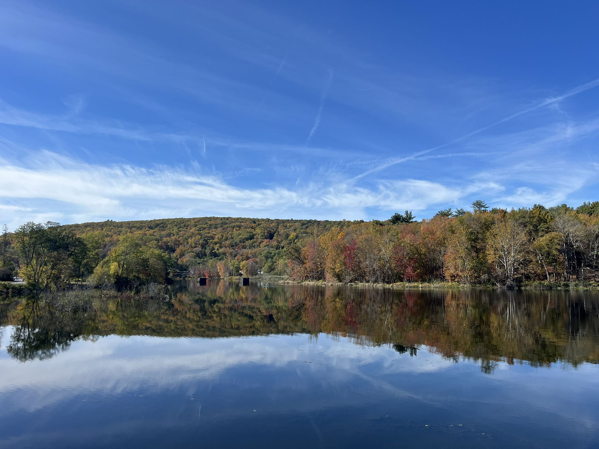 Calm lake reflecting autumn trees under a bright blue sky with wispy clouds. - Farmington River and Nepaug Reservoir Loop