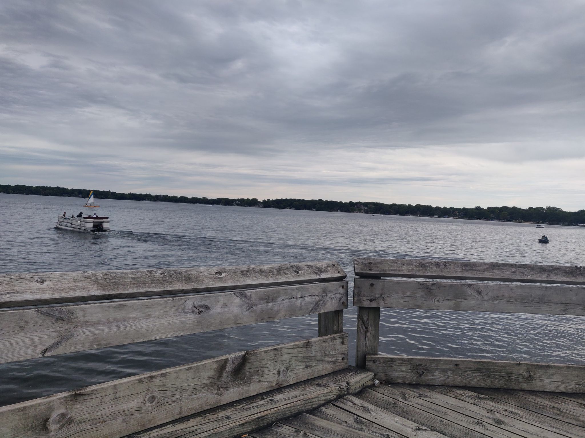 A wooden pier overlooks a wide lake with a boat moving under cloudy skies. - Elm Point loop from Bean Lake State Natural Area