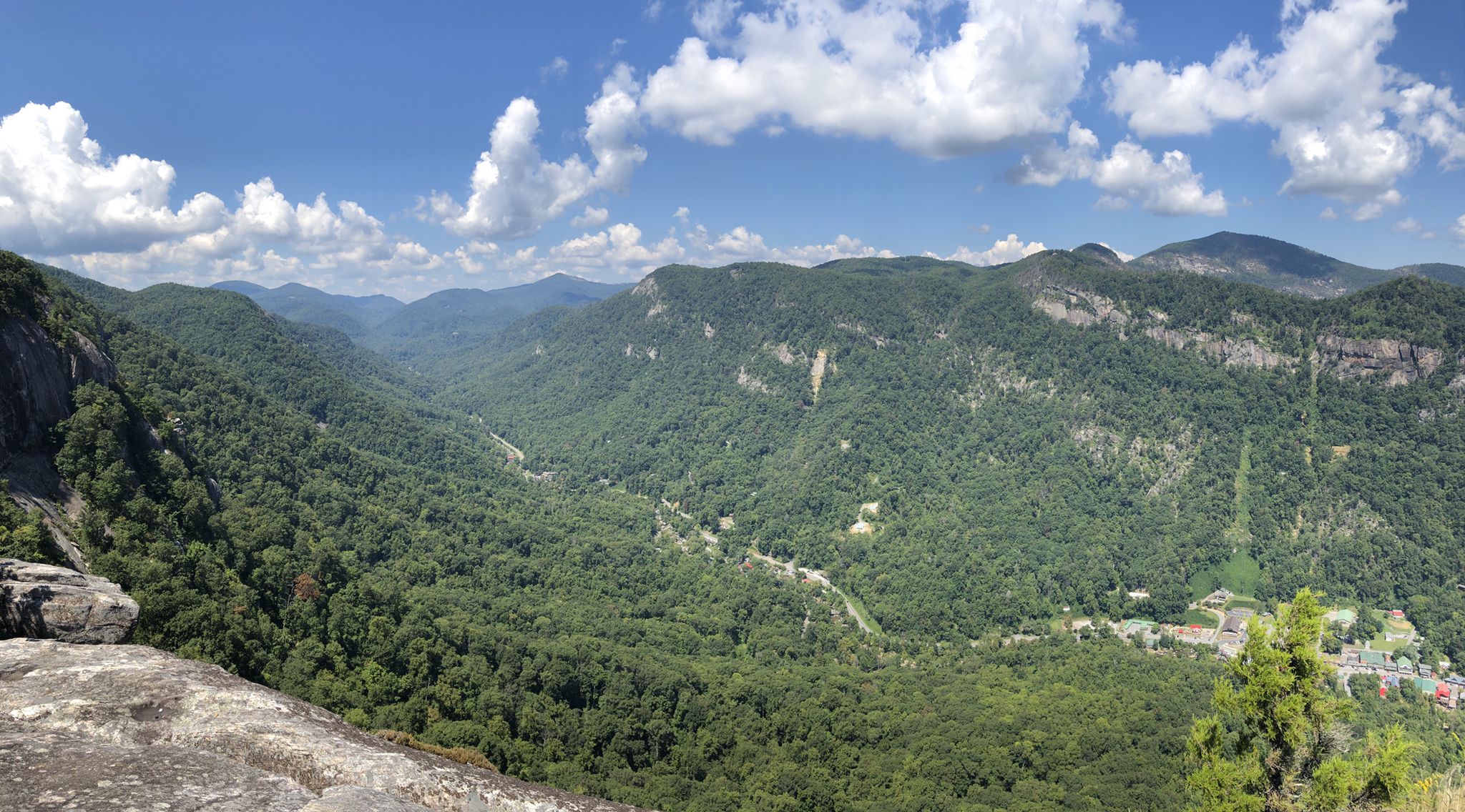 Panoramic view of a wide, forested mountain valley under a blue sky. Bright daylight. - Four Season Trail to Upper & Lower Hickory Nut Falls – Chimney Rock State Park, North Carolina