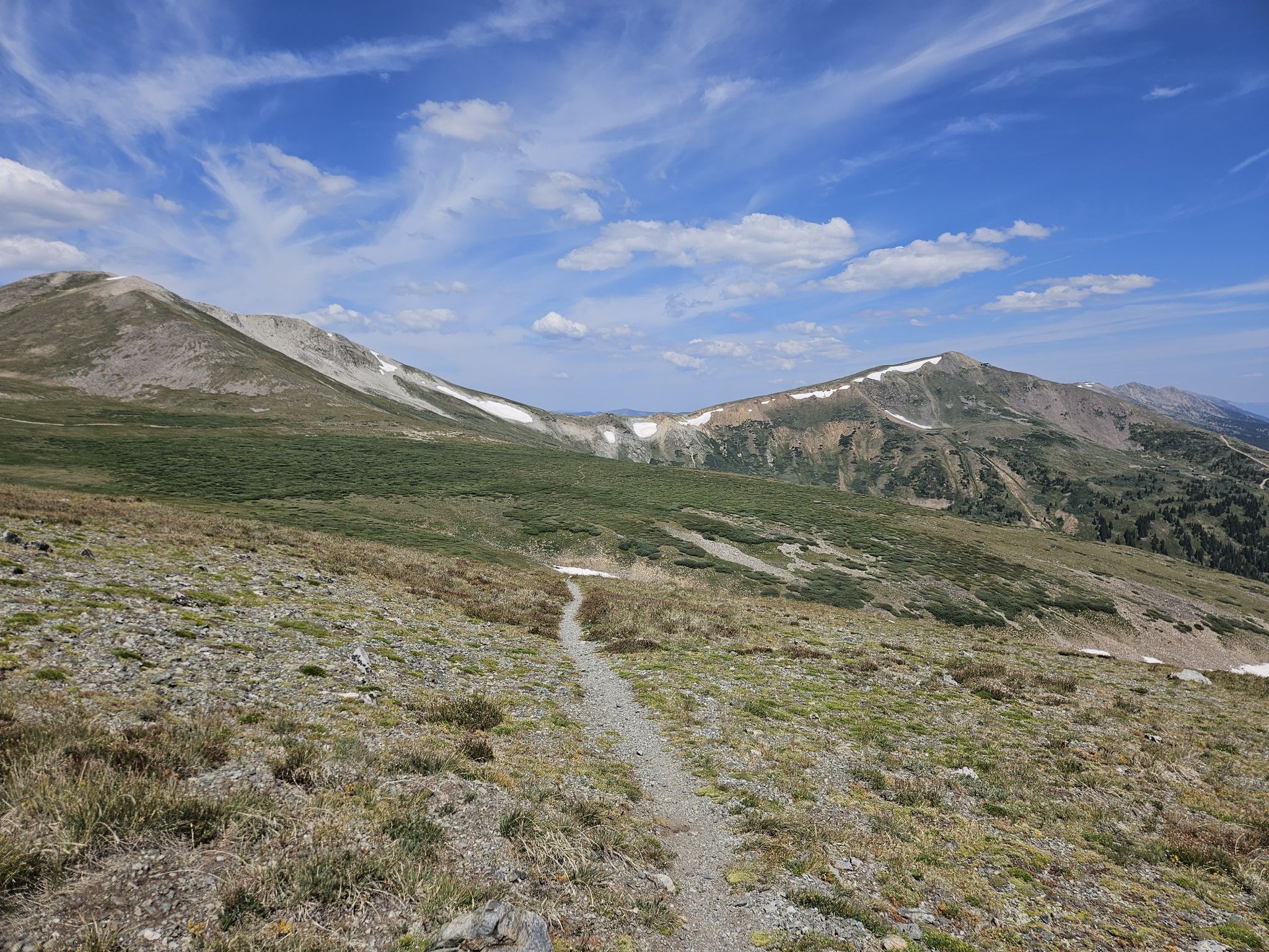 A narrow dirt path traverses a vast, sunny, rocky mountain landscape under blue sky. - Peak 9, Wheeler and Burro Trail Loop
