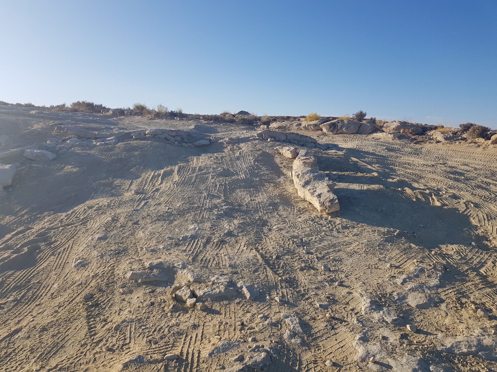 Arid, rocky terrain with tire tracks under a clear blue sky. - Alstrom Point via Smoky Mountain Road