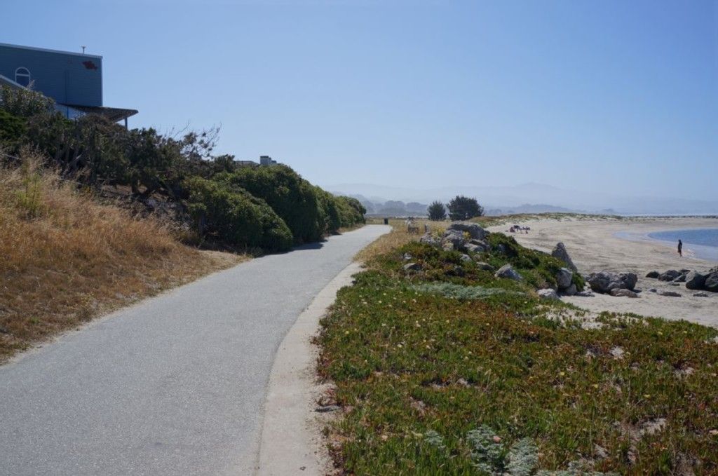 Paved path alongside a sandy beach with ocean and distant hills. - Pillar Point Harbor & Pier – El Granada Beach loop from El Granada