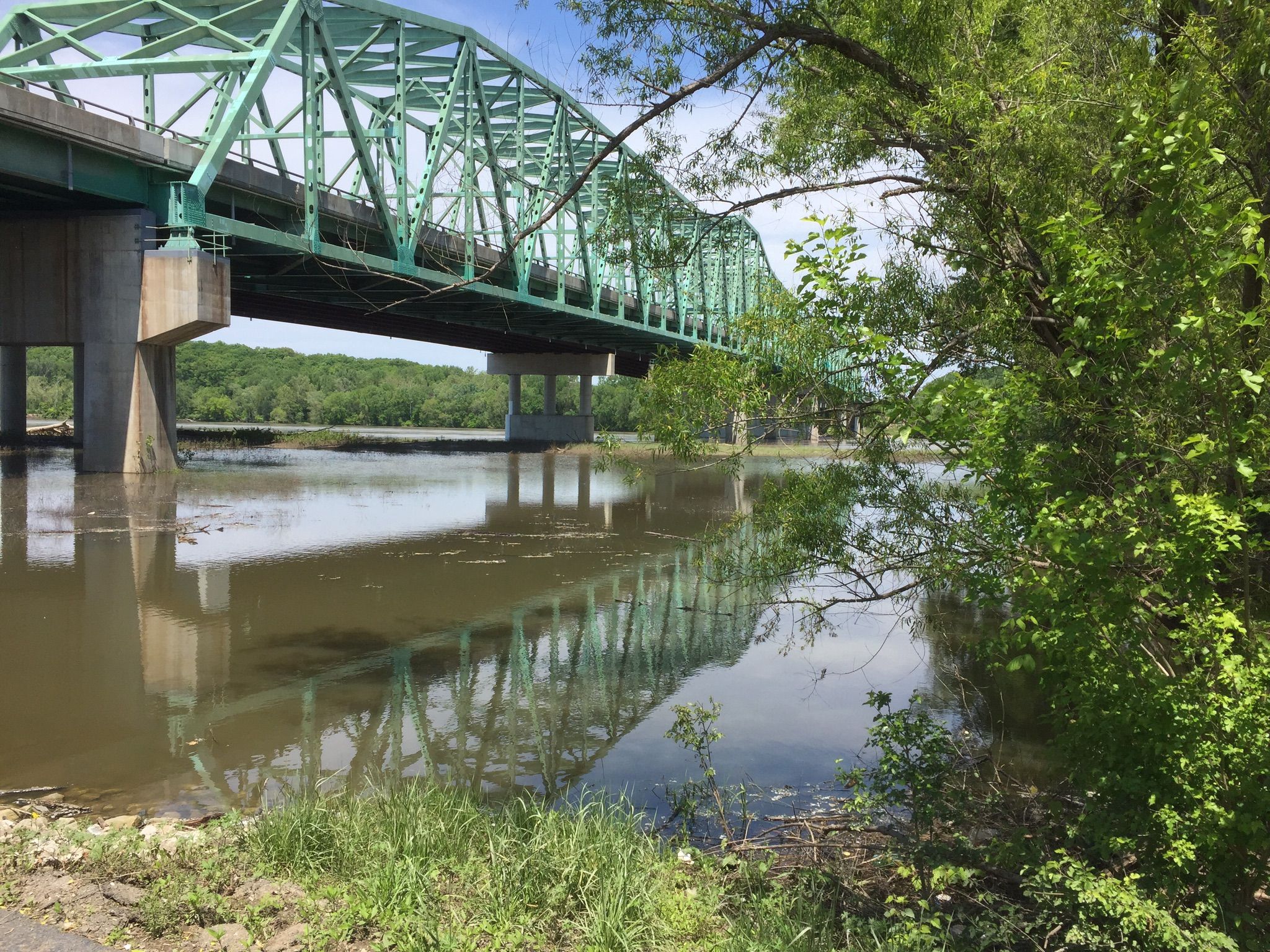 A green truss bridge spans a wide, muddy river on a sunny day. - Busch Greenway Trail – Katy Trail loop from Weldon Spring Heights