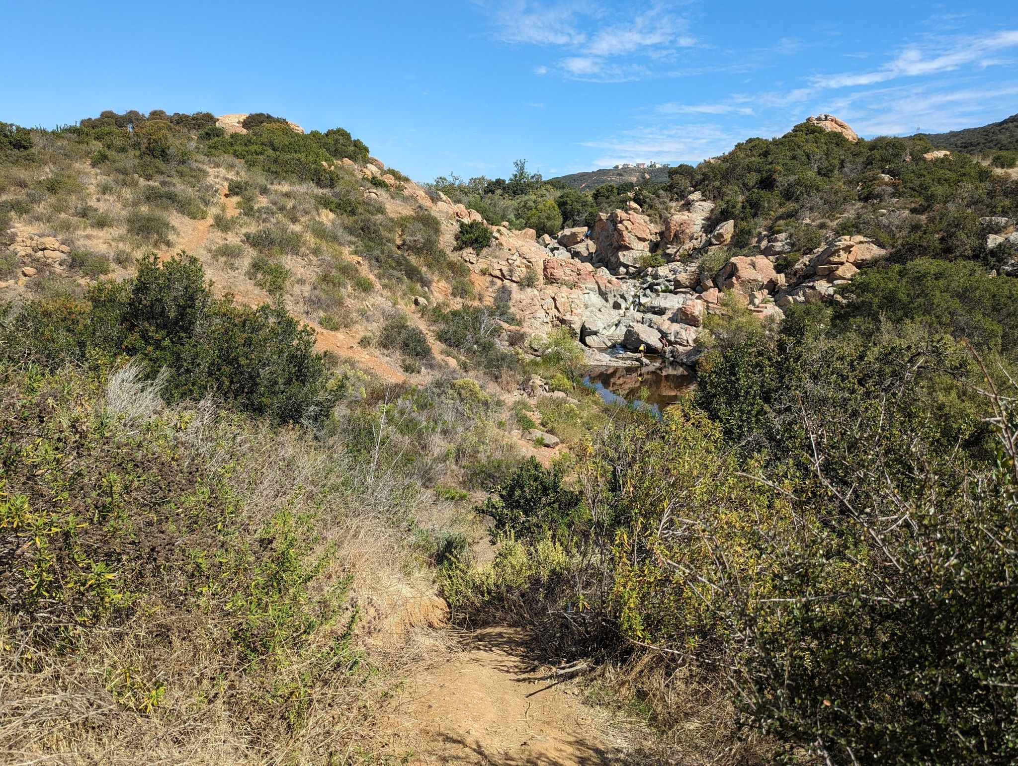 Sunny view of rocky hills with scrub brush and a small pond. - Los Peñasquitos Falls – Los Peñasquitos Waterfall loop from Mira Mesa