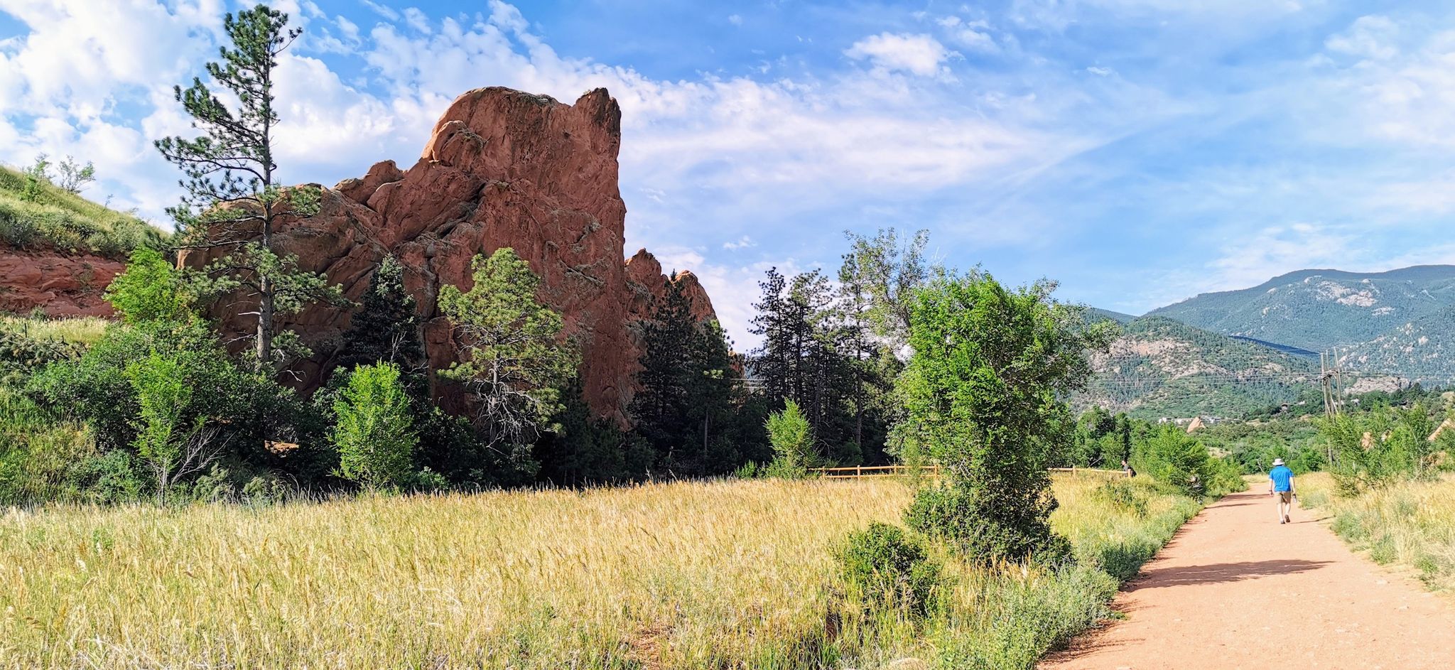 A person walks on a dirt path beside a golden field and red rock. - Red Rock Canyon Open Space – Bear Creek loop from Pulloff Number 4