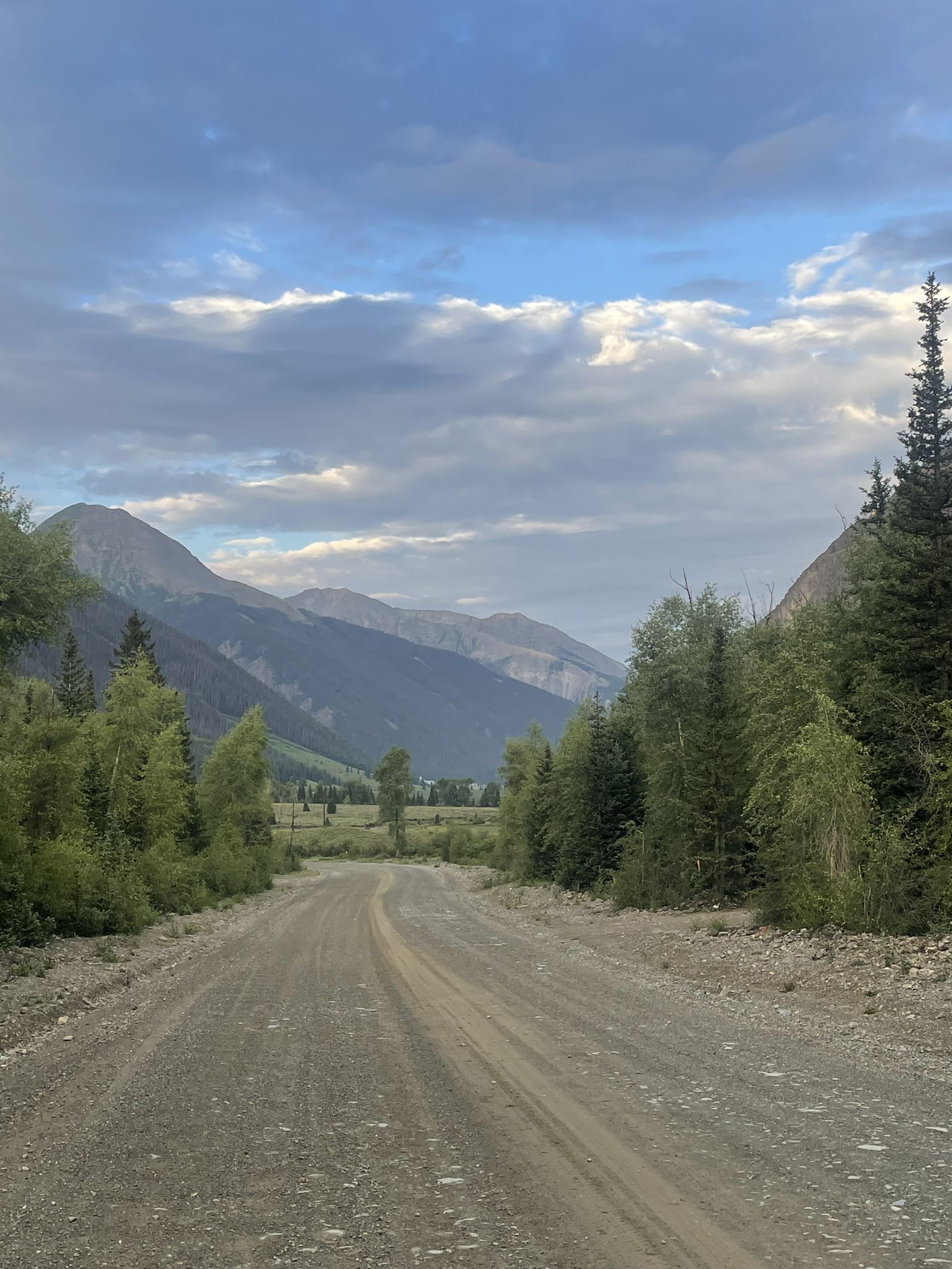 A dirt road leads through a mountain valley under a cloudy sky. - Silverton – Eureka loop from Silverton