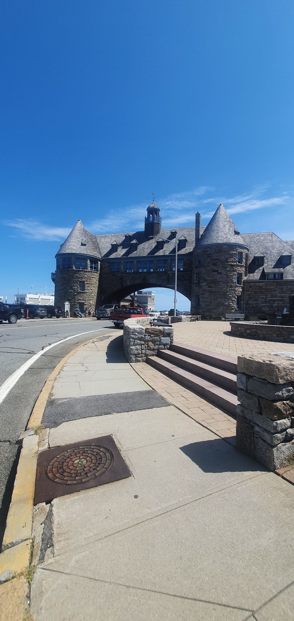 Stone building with archway and turrets, bright blue sky, road, and sidewalk. - Scarborough South State Beach – Black Point Main Trail loop from Narragansett