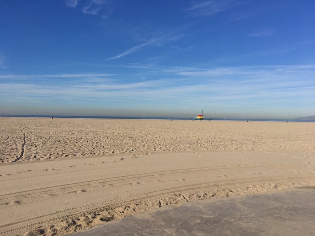 Vast sandy beach under a clear blue sky with a distant lifeguard tower. - Muscle Beach Venice – Venice Beach Skatepark loop from Downtown Santa Monica