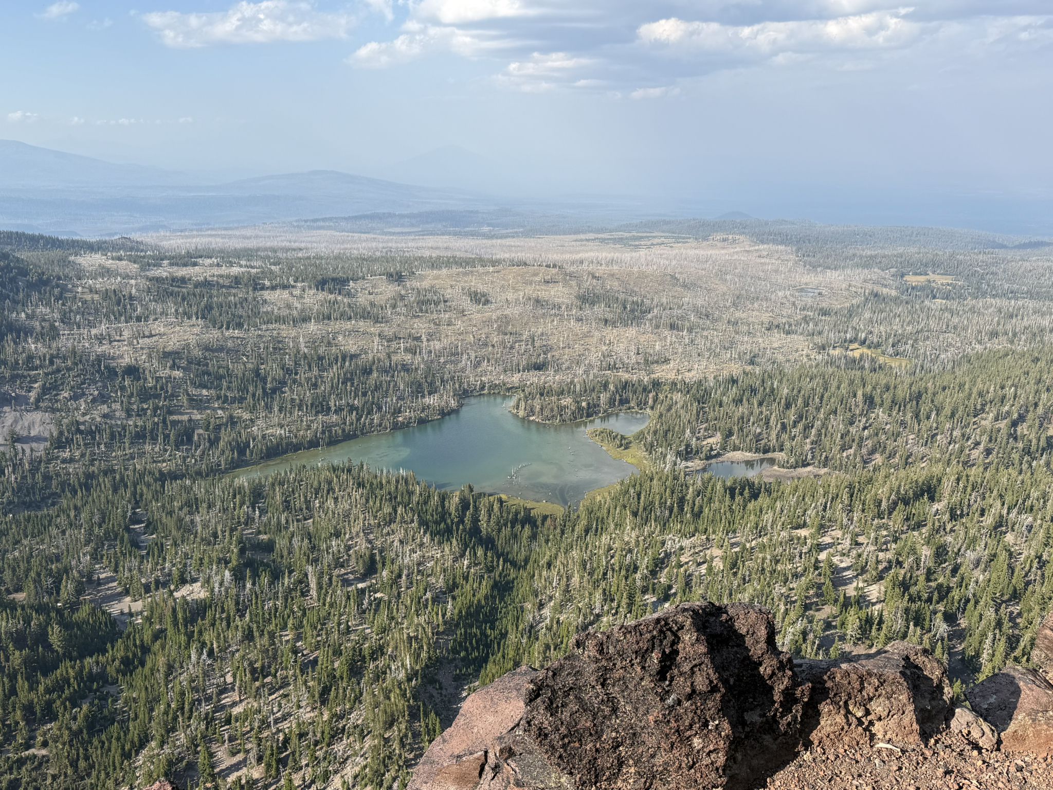 Aerial view of a small lake nestled within a vast green forest. - Tam McArthur Rim Trail to Broken Hand