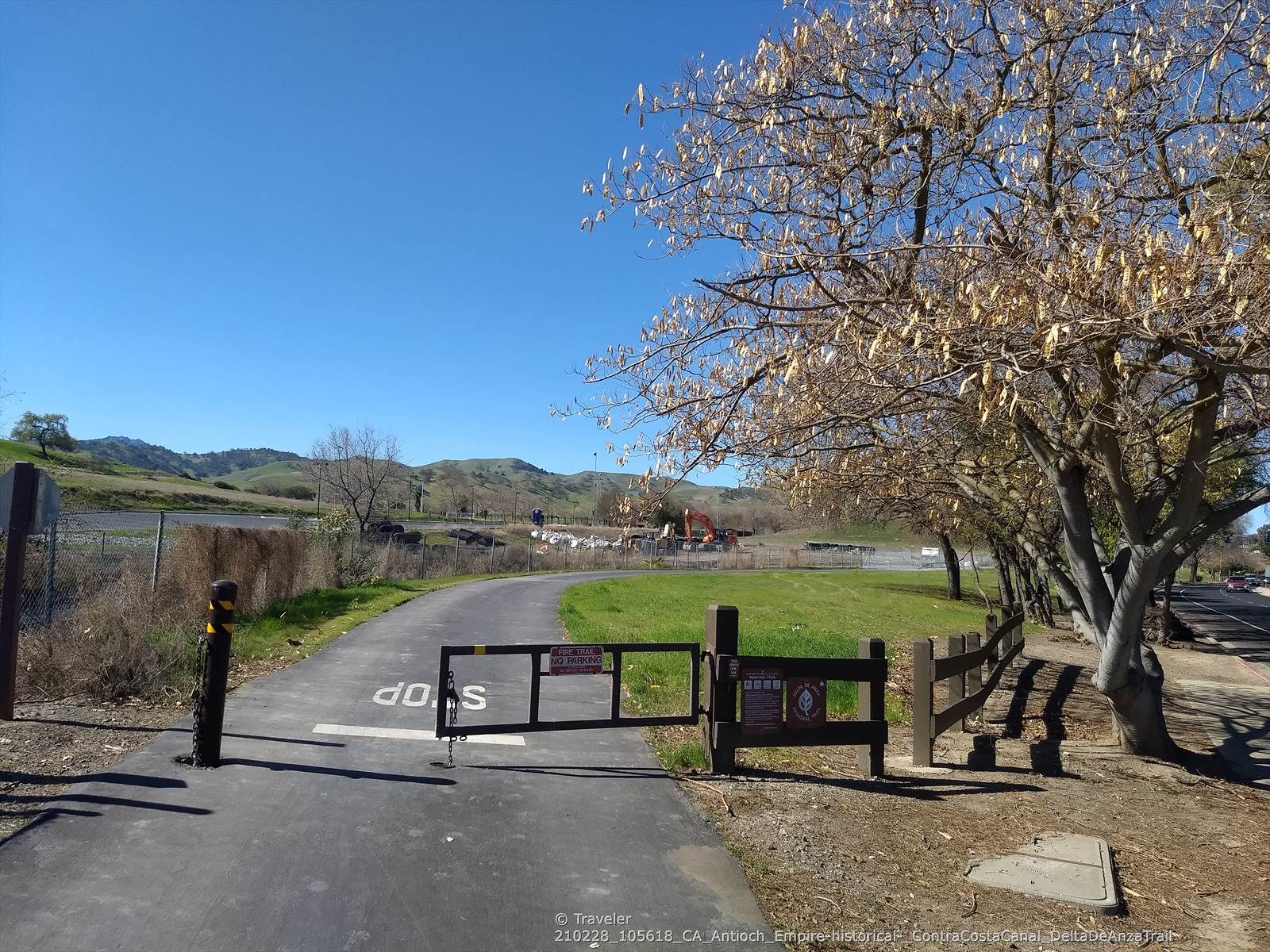 Paved path with a gate and stop sign under a clear blue sky. - Clayton Ranch loop