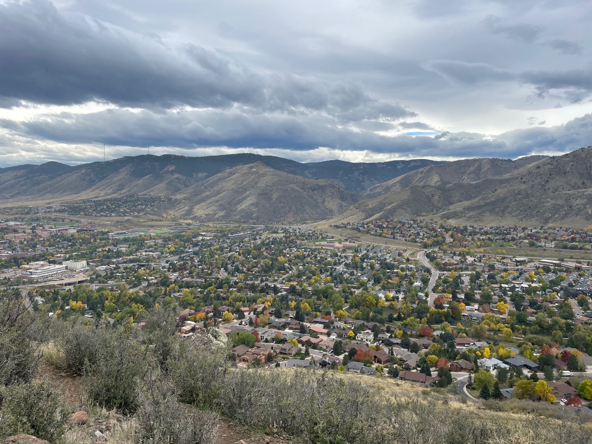 Overcast view of a town nestled in a valley surrounded by mountains. - Tilting Mesa Trail – North Table Mountain loop from Golden