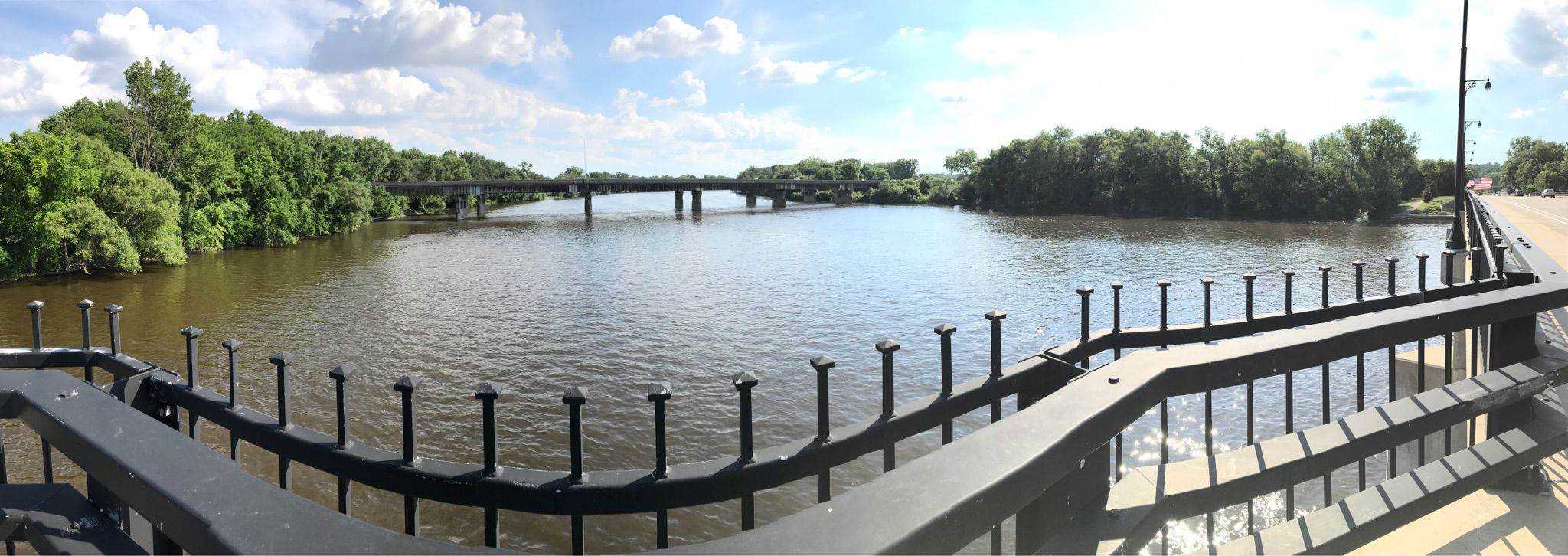 Wide river view from a bridge, with distant bridges and green trees. - Fred Meijer White Pine Trail