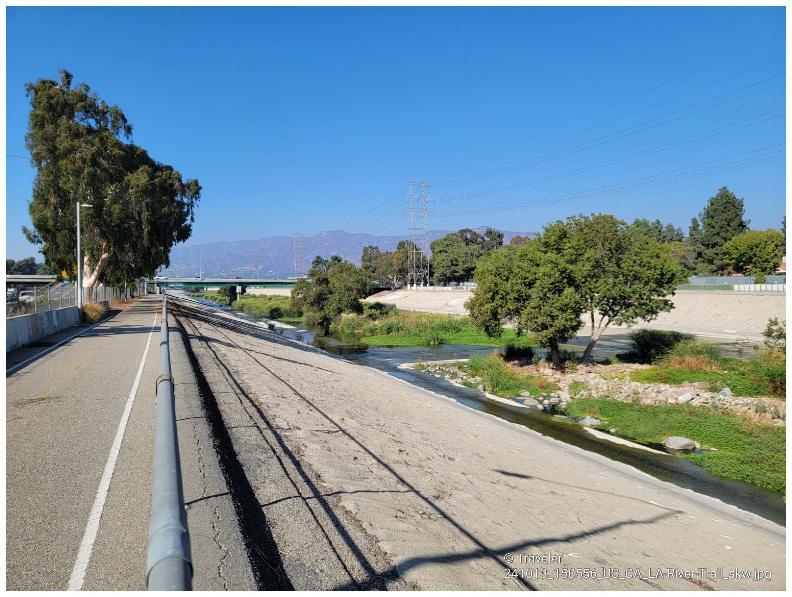 Paved path and dirt bank beside a river with trees and mountains, sunny. - Griffith Park Drive – Red Car Bridge loop from Burbank Airport–South