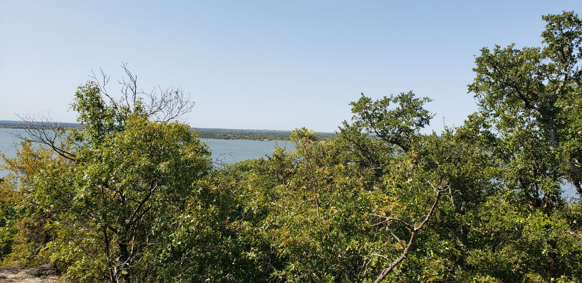 Lush green trees and bushes frame a wide view of a lake. - Eagle Mountain Northwest Loop