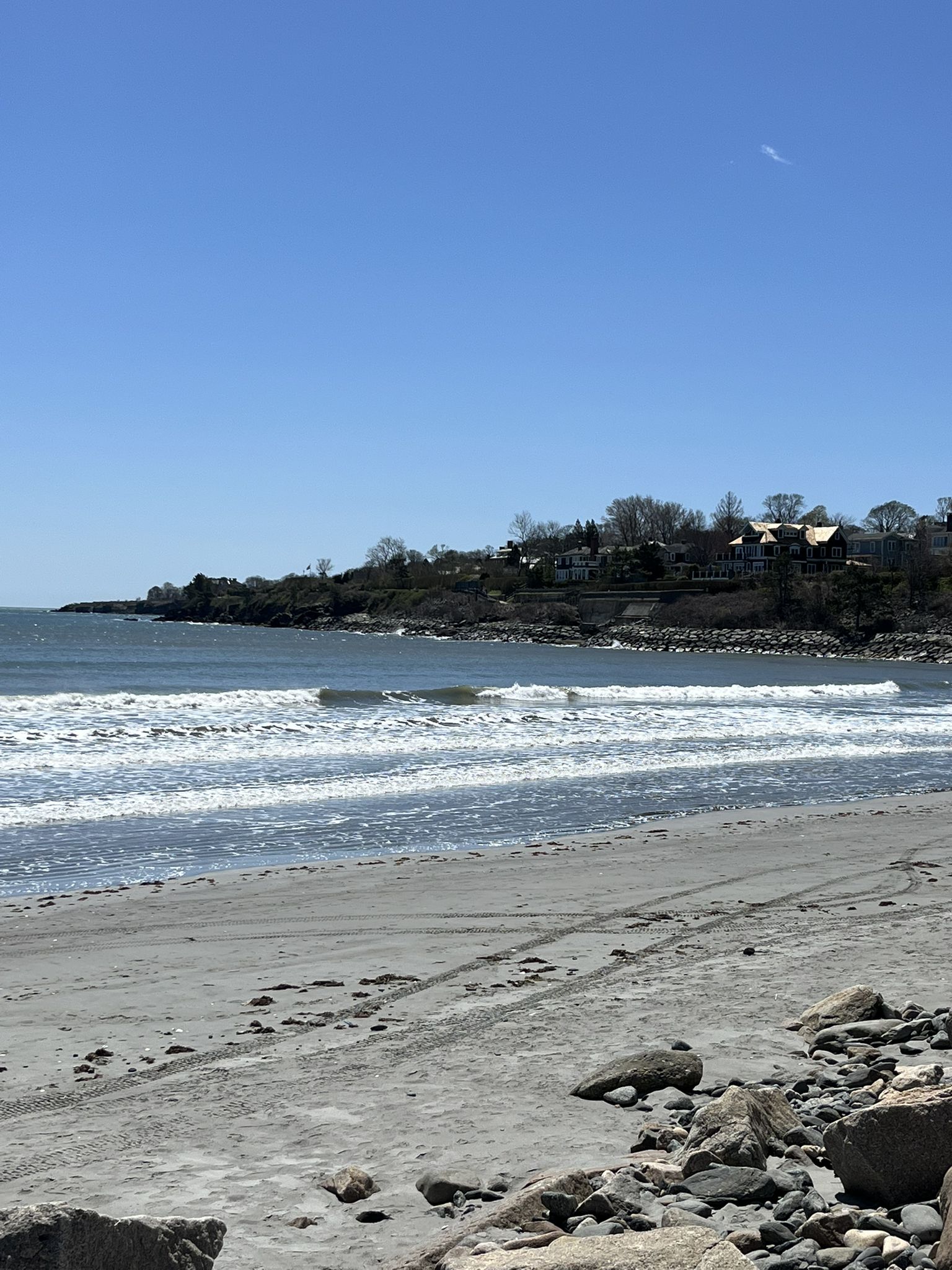 Sunny sandy beach with ocean waves and houses on a distant green hill. - Green End Pond loop from Newport