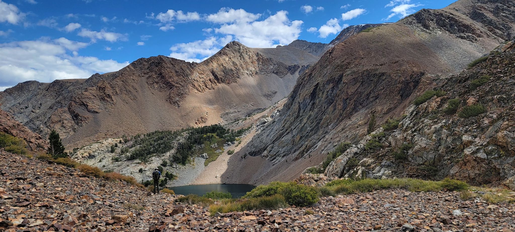 A small lake nestled in a vast mountain valley with rocky, rugged slopes. - Bloody Canyon Trail