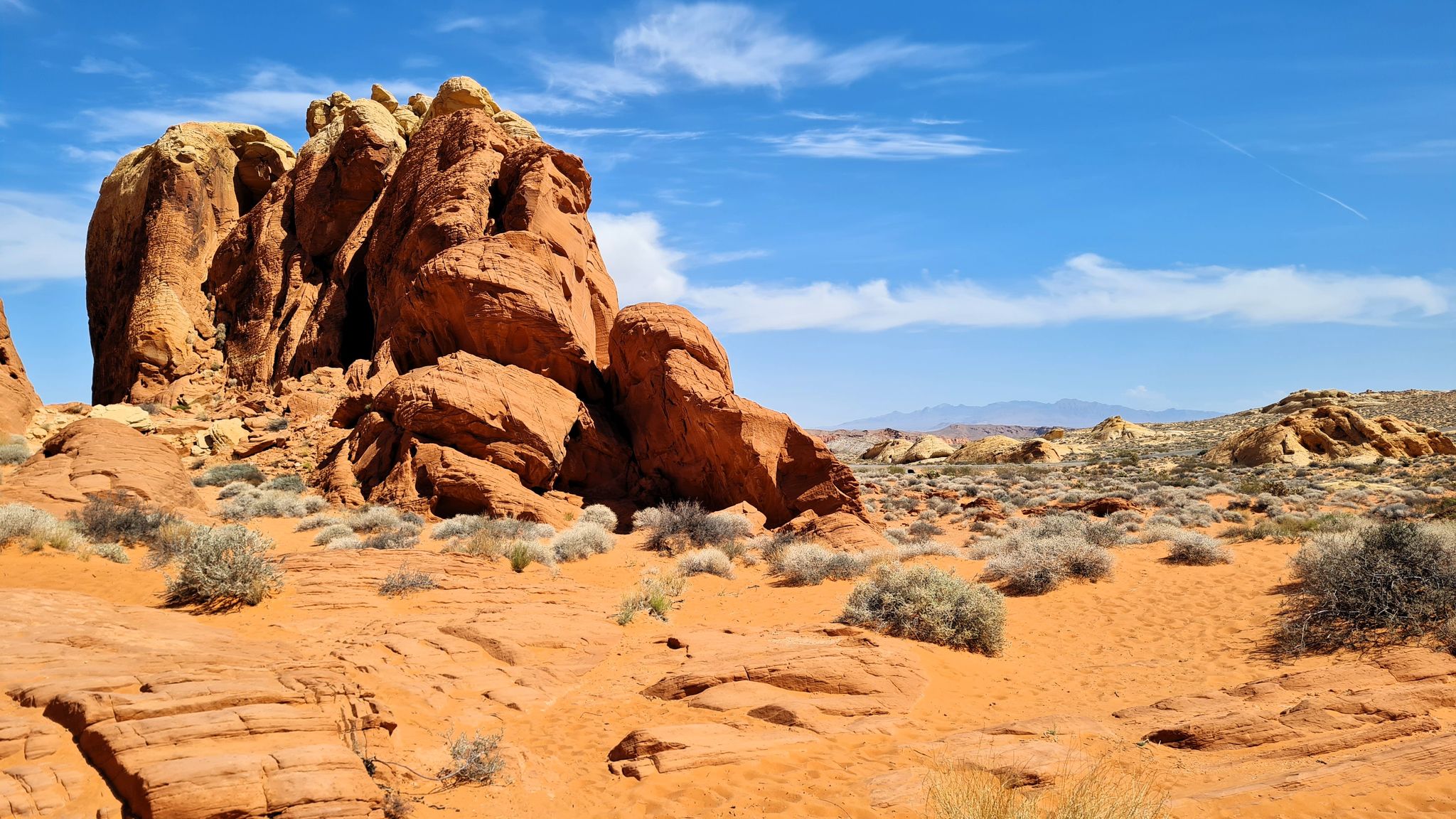 Large red rock formations in a sandy desert landscape under a clear blue sky. - Rainbow Vista Trail