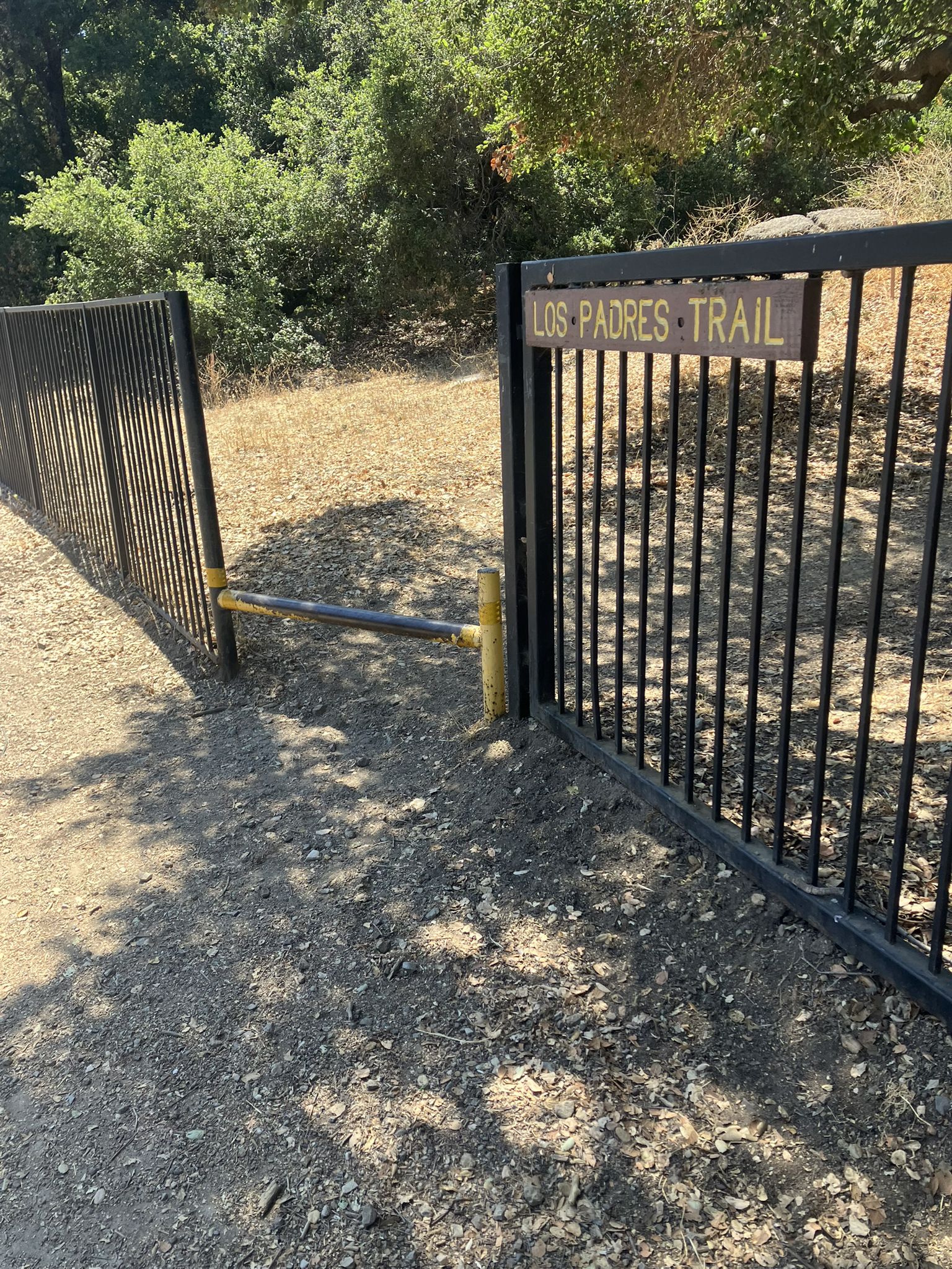 A black metal gate with a wooden sign on a sunny dirt path. - Vista Loop Trail – Los Padres Open Space loop from American Eagle Outfitters