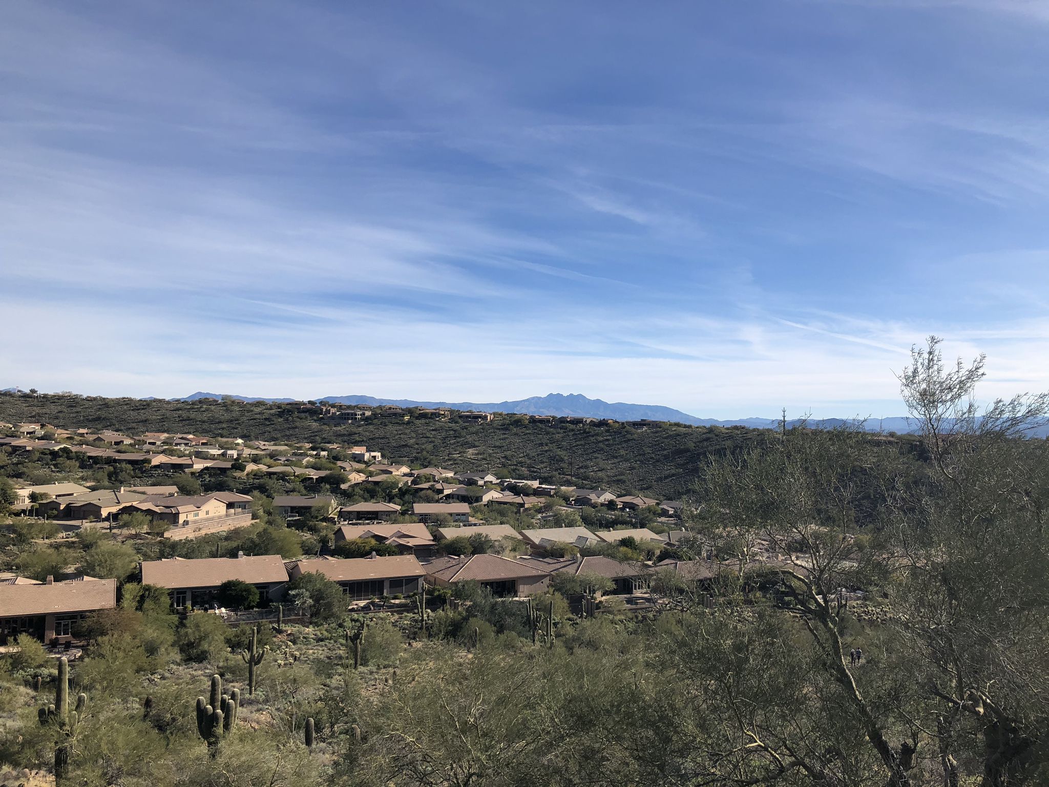 Houses nestled in a desert valley with distant mountains under a bright sky. - Sunrise Peak via Sunrise Trail