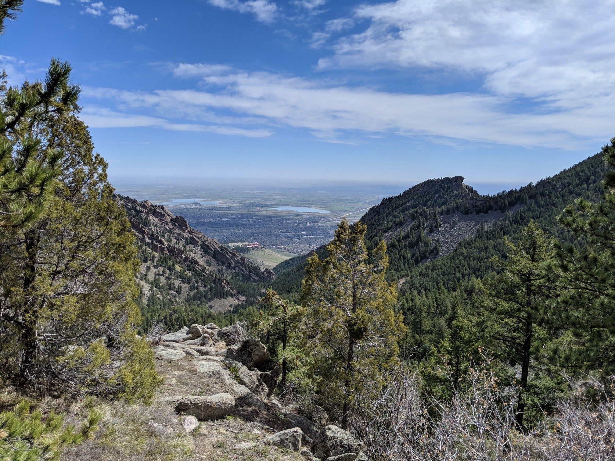 Mountain valley view with distant city, green trees, and blue sky. - Boulder Skyline Traverse