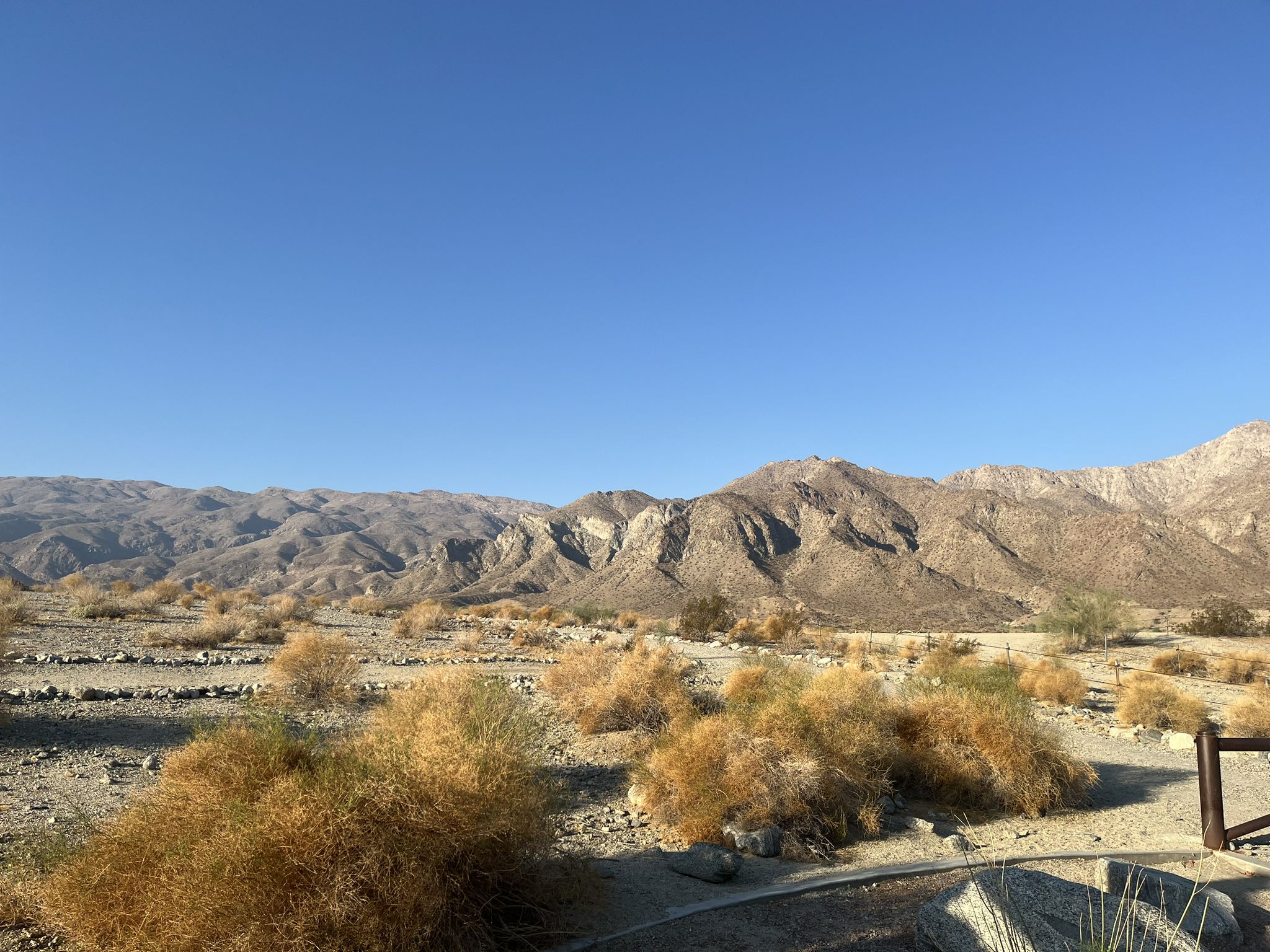 Arid desert landscape with dry brush and distant mountains under a clear sky. - Cove Oasis loop from Citrus Plaza