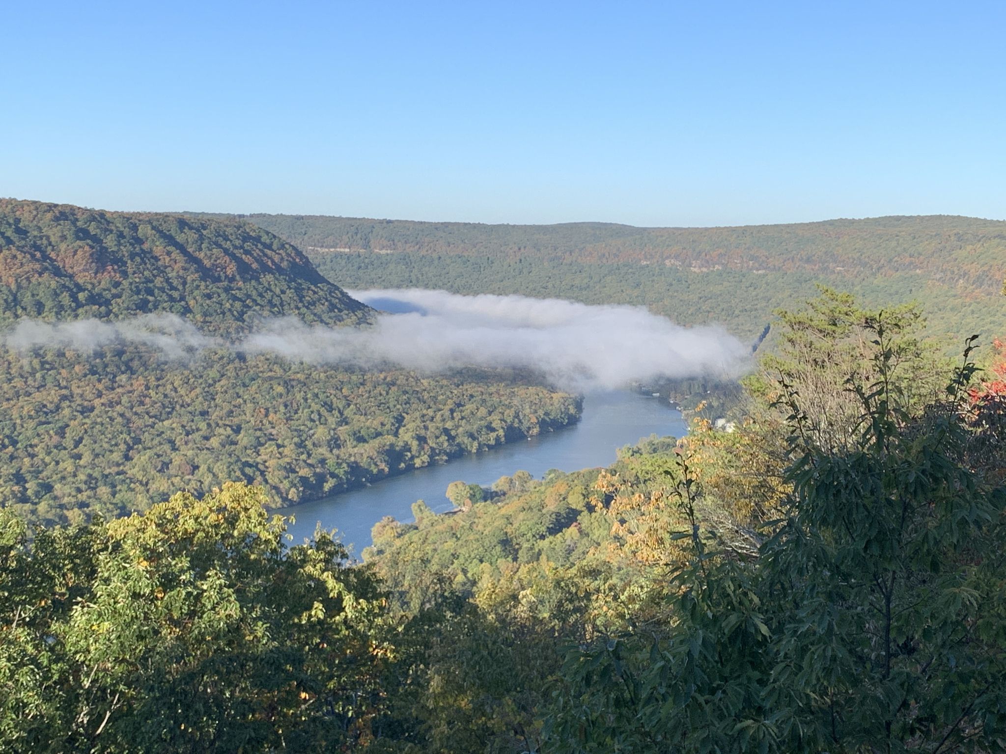 River and forested valley partially obscured by low-lying fog on a clear day. - Rainbow Falls – Rainbow Lake Wilderness loop from Signal Mountain