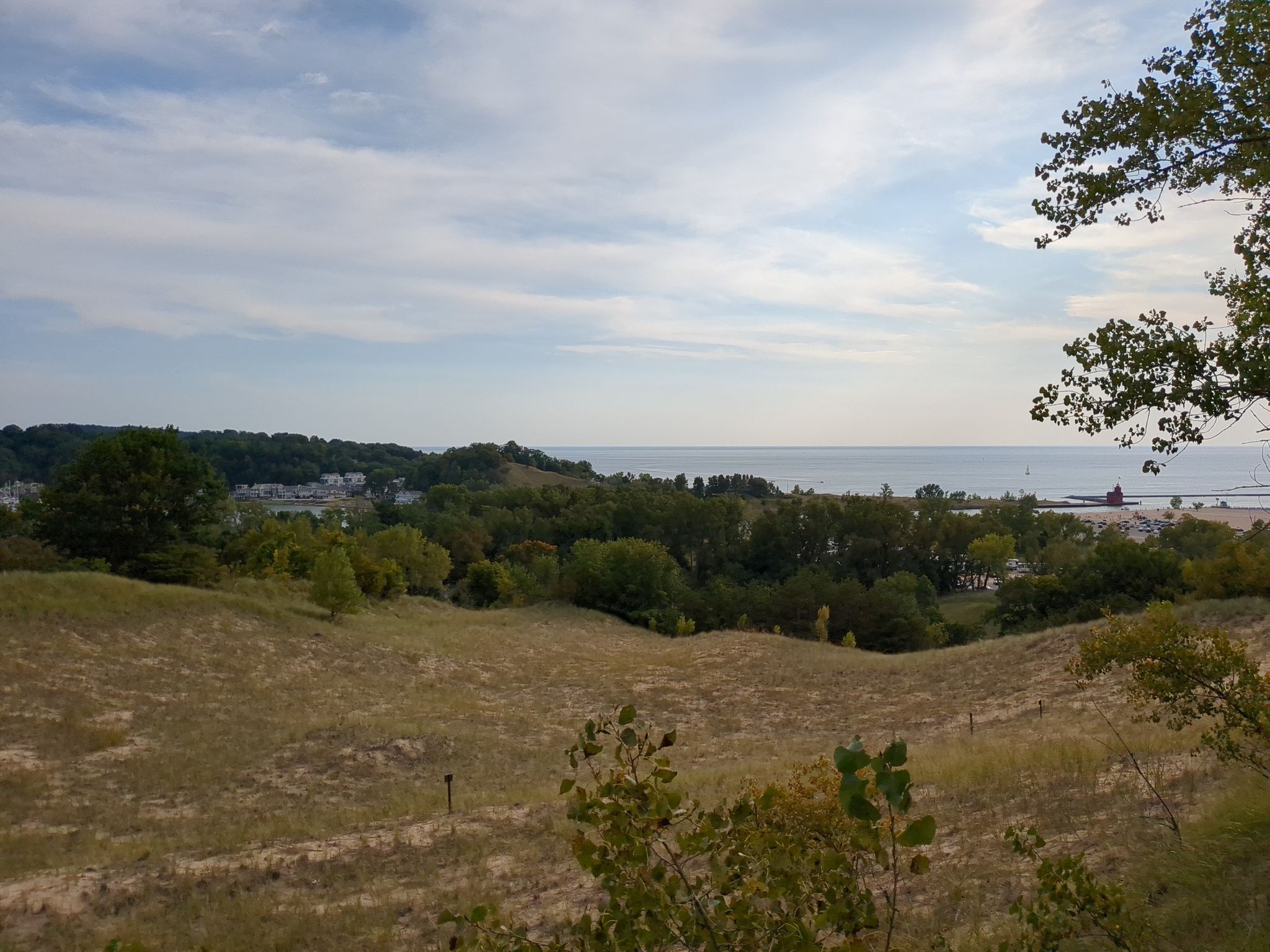 Rolling grassy dunes lead to distant water under a partly cloudy sky. - Mount Pisgah Dune Boardwalk