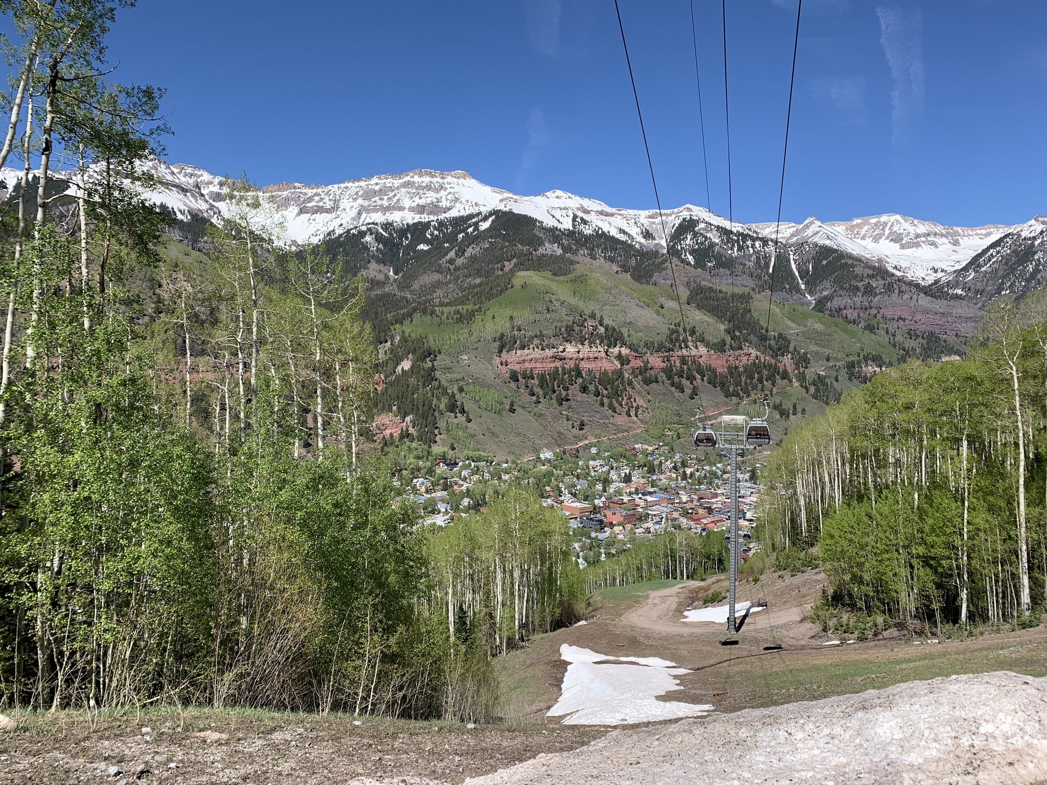 Sunny view of snow-capped mountains, a town, and a ski lift. - Prospect Loop Trail