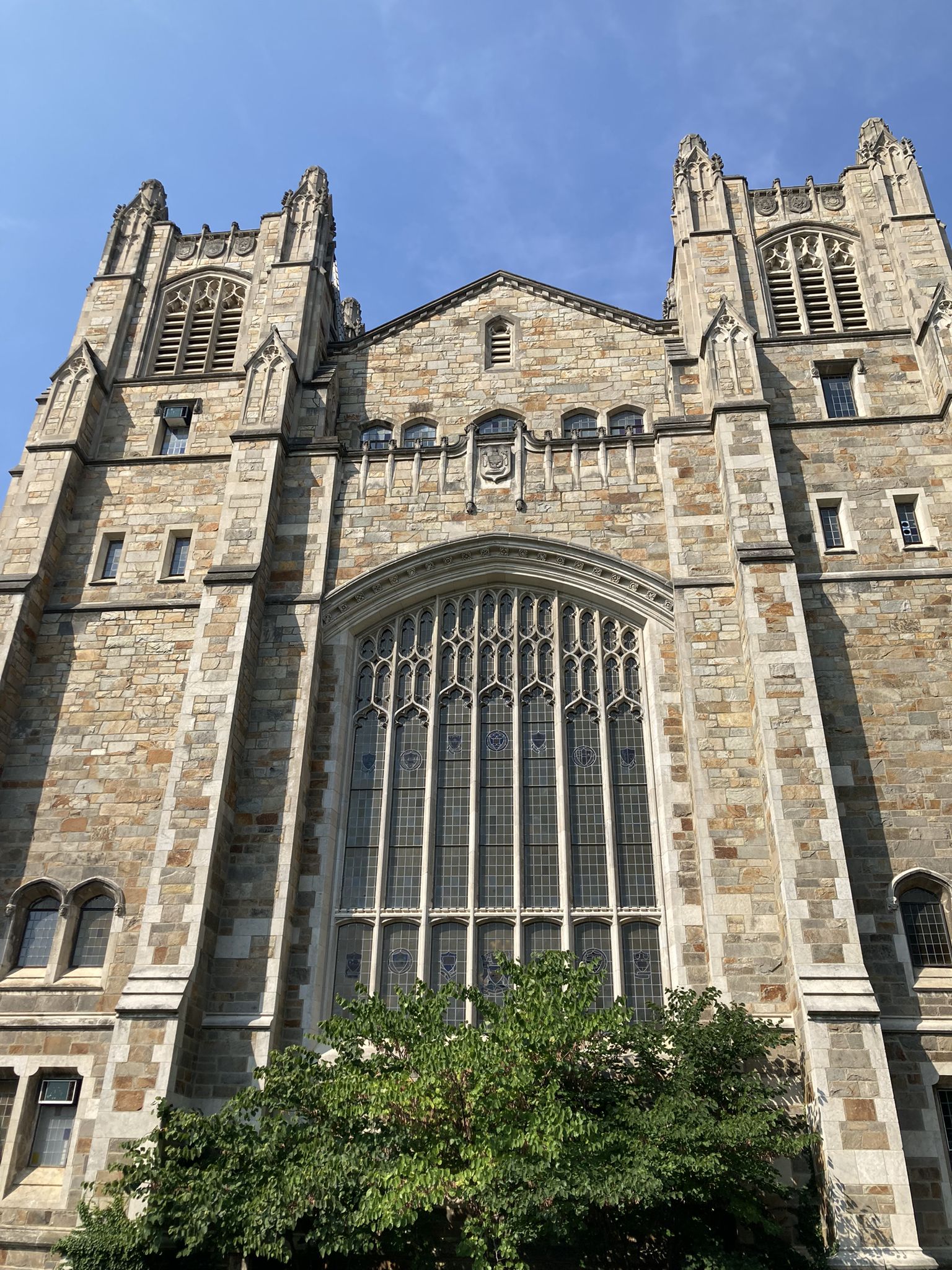 Tall stone building with gothic architecture and large arched windows under blue sky. - Ann Arbor to Jerusalem loop