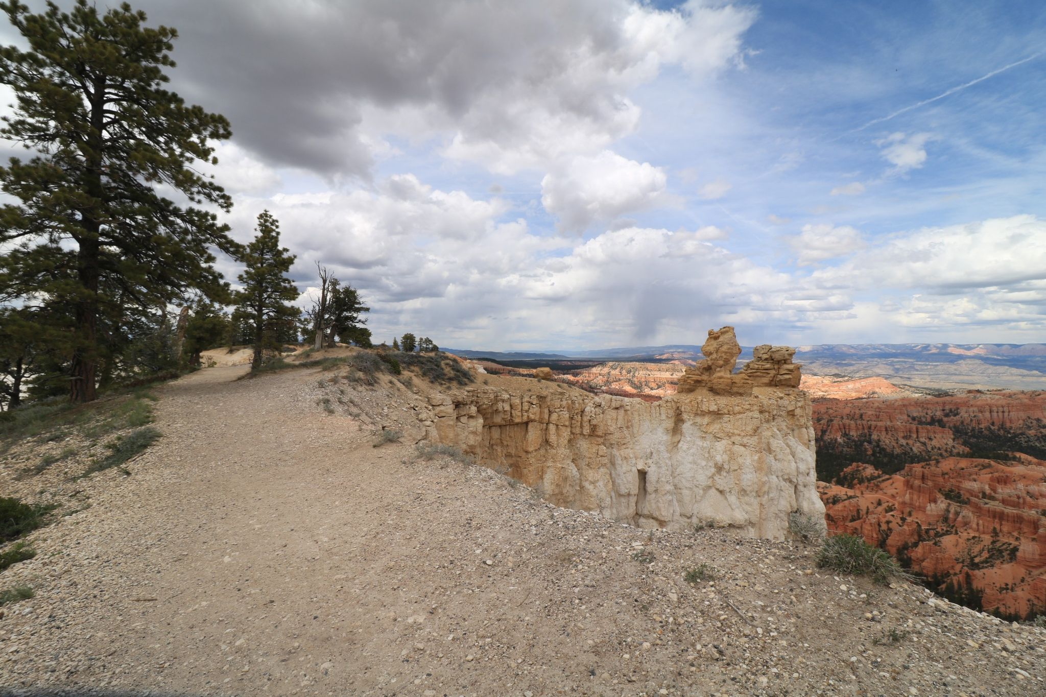 Dirt path leading to unique rock formations overlooking a distant canyon. - Lower Inspiration Point – Liberty Castle loop from Bryce Canyon Lodge