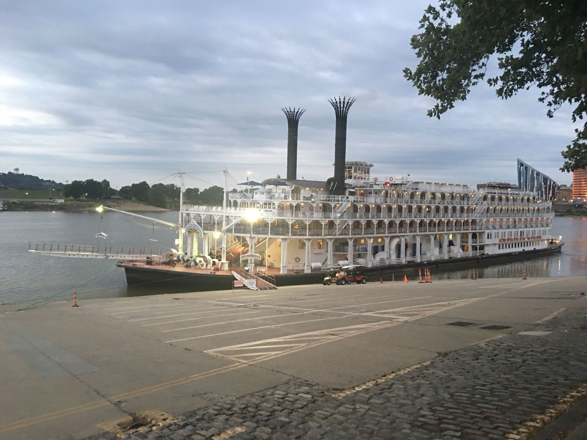 Large white paddlewheel boat docked on a river at dusk. - Public Landing – Serpentine Wall loop from Cincinnati