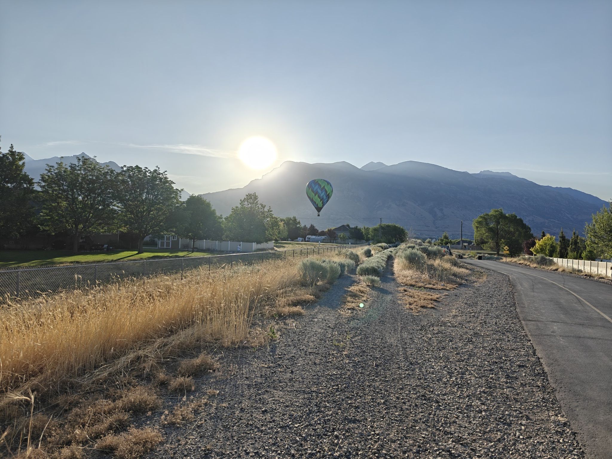 Hot air balloon rising over mountains and fields during a bright sunrise. - Murdock Canal Trail loop from Mitchell Hollow Park