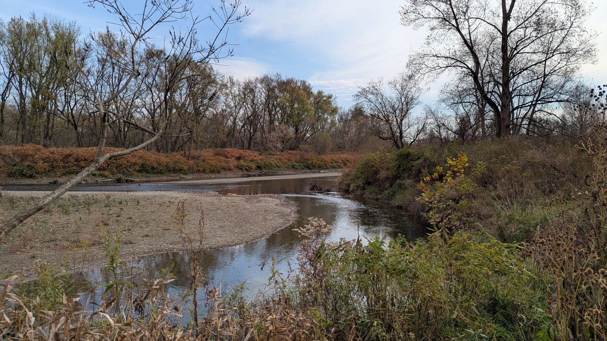 A winding river with sandy banks, surrounded by autumn trees under a cloudy sky. - Buckeye and Towpath Trail Loop