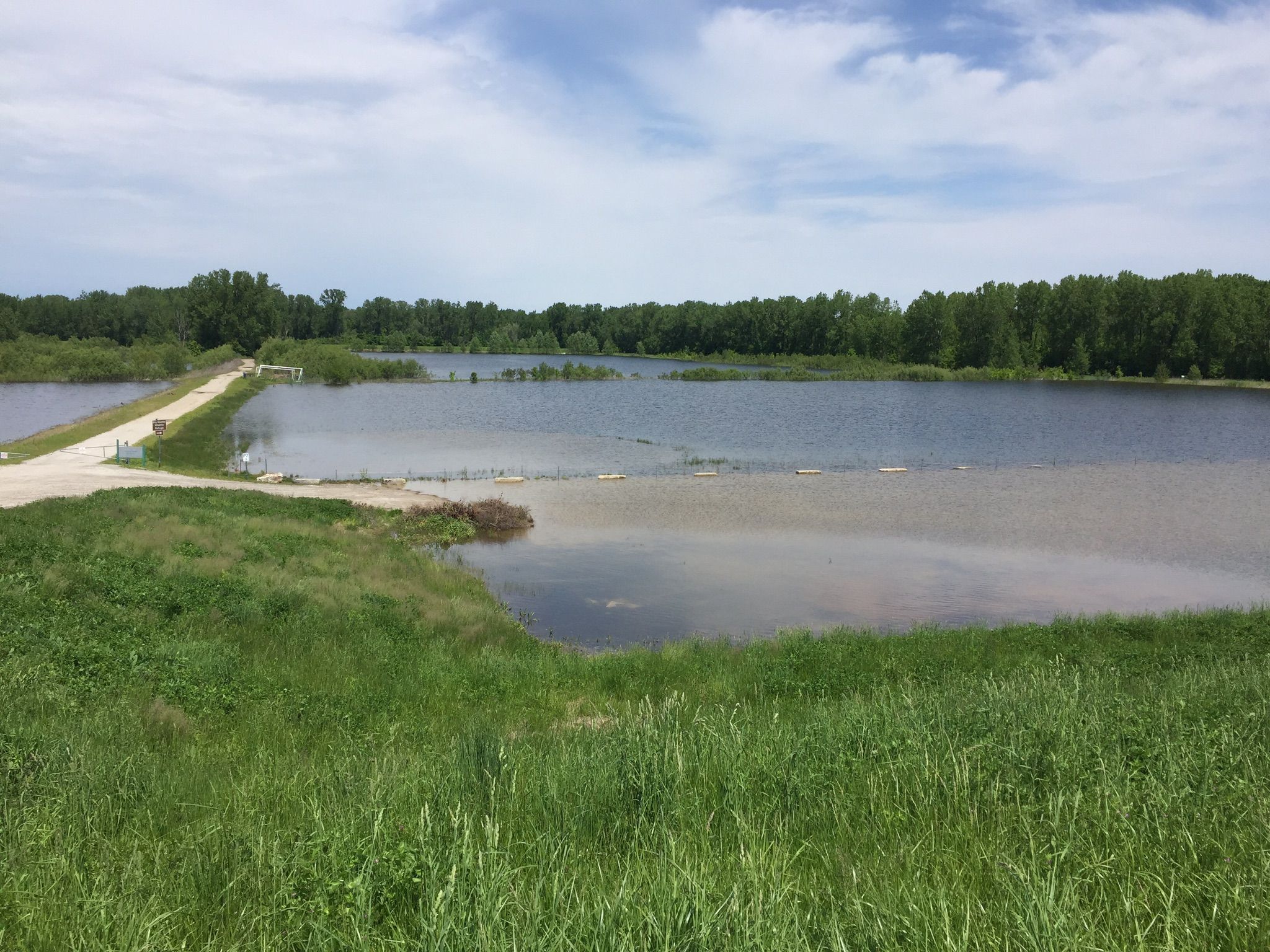A wide lake with a narrow causeway, surrounded by green trees. - Katy Trail – Katy Trail loop from Chesterfield Airport at Chesterfield Industrial