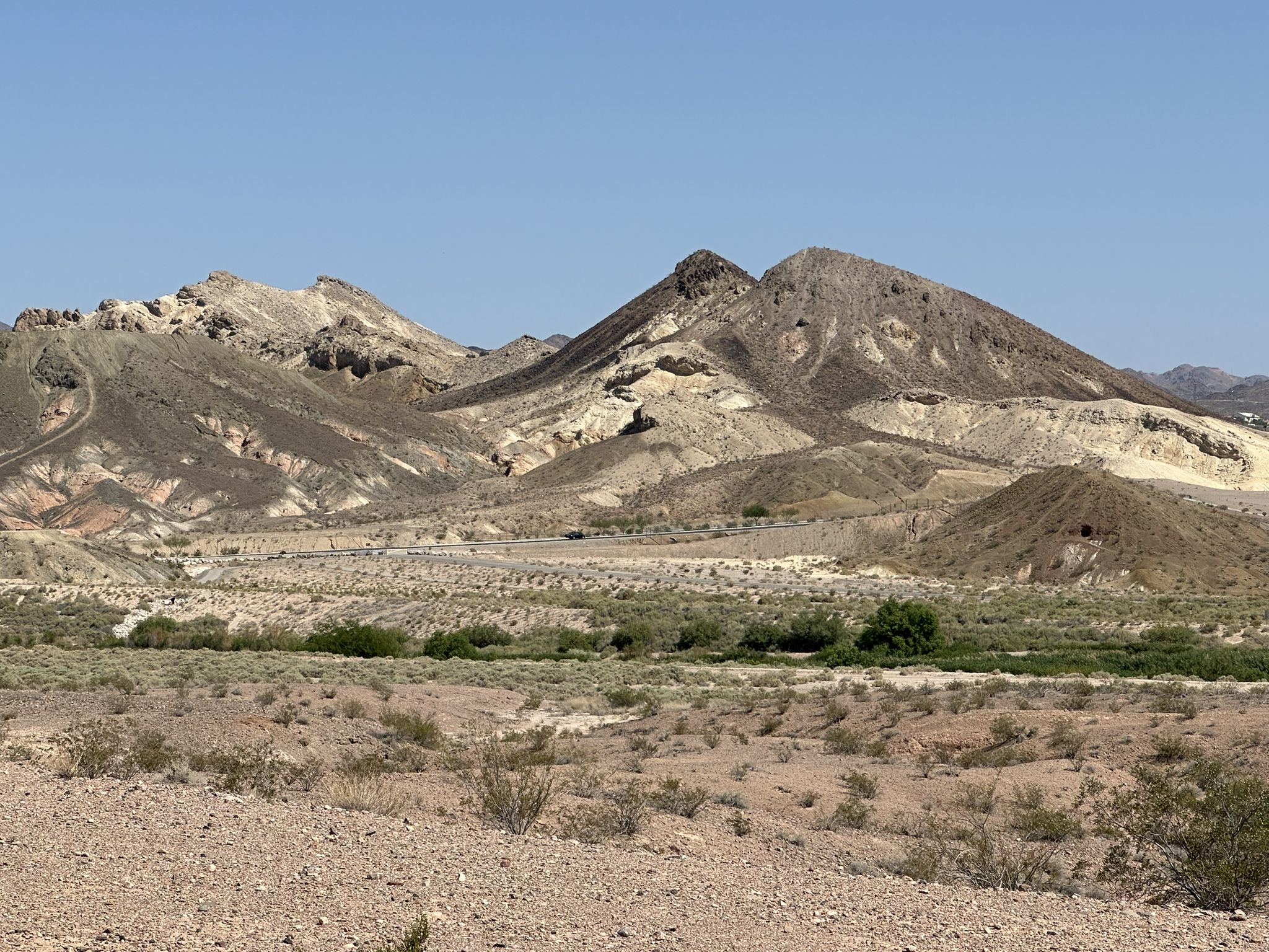Arid desert landscape with rugged, colorful mountains under a clear blue sky. - Wetlands Park Loop Trail