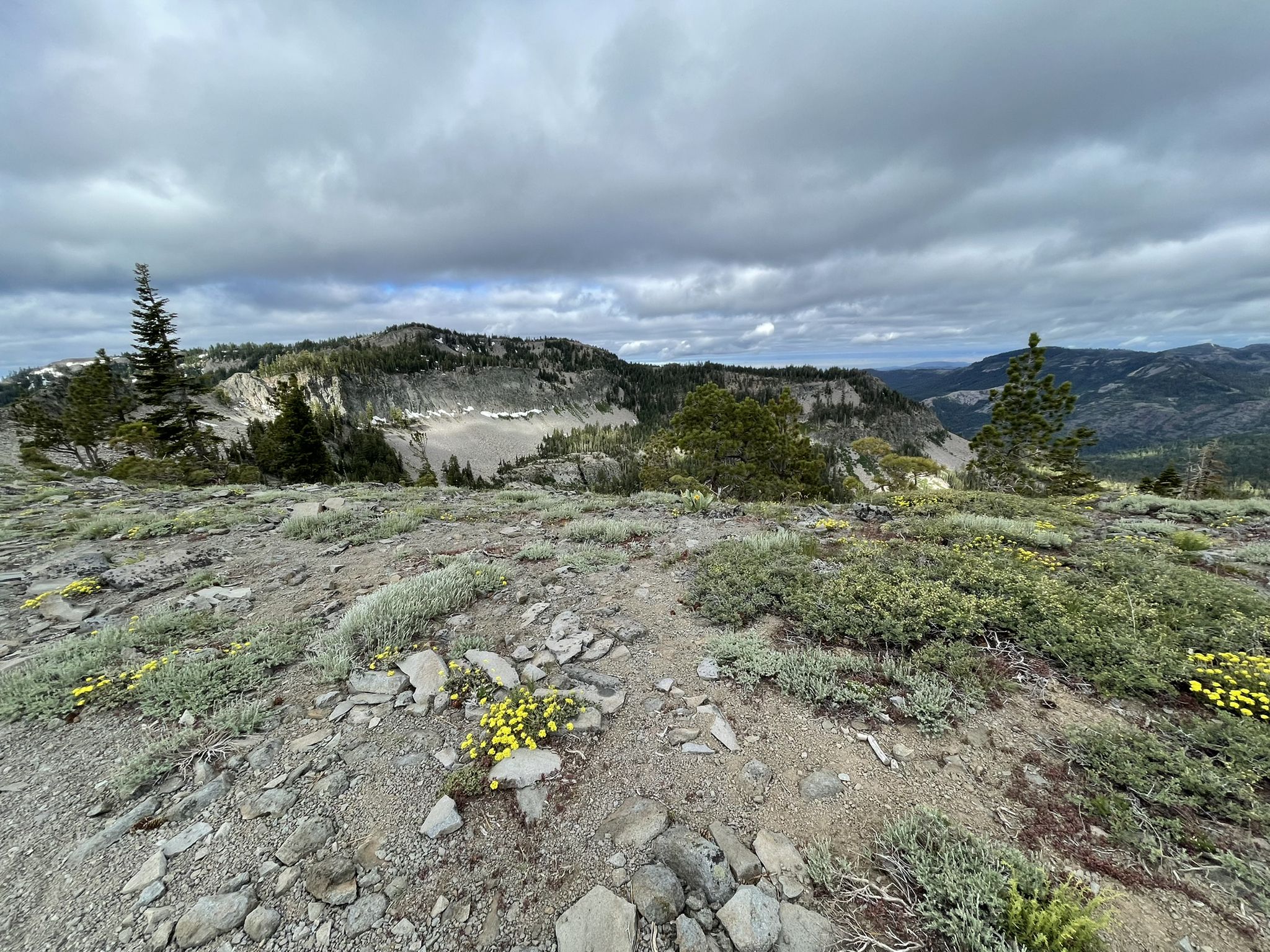 Rocky mountain landscape under cloudy skies, with distant peaks and sparse vegetation. - Tahoe Rim Trail: Barker Pass to Tahoe City