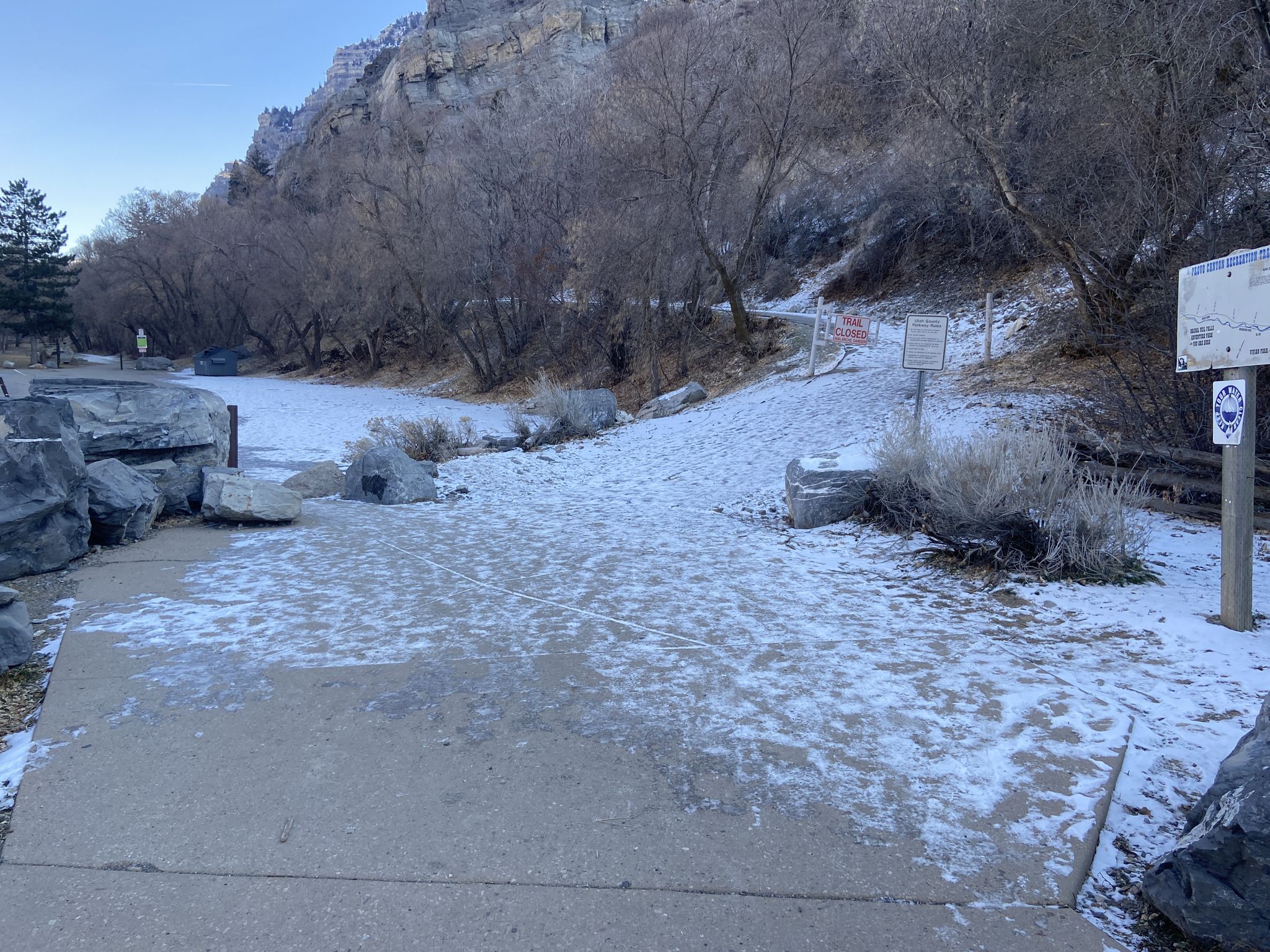 Snow-covered paved path next to a rocky hillside and bare winter trees. - Provo River Parkway – Bridal Veil Falls loop from Provo Central
