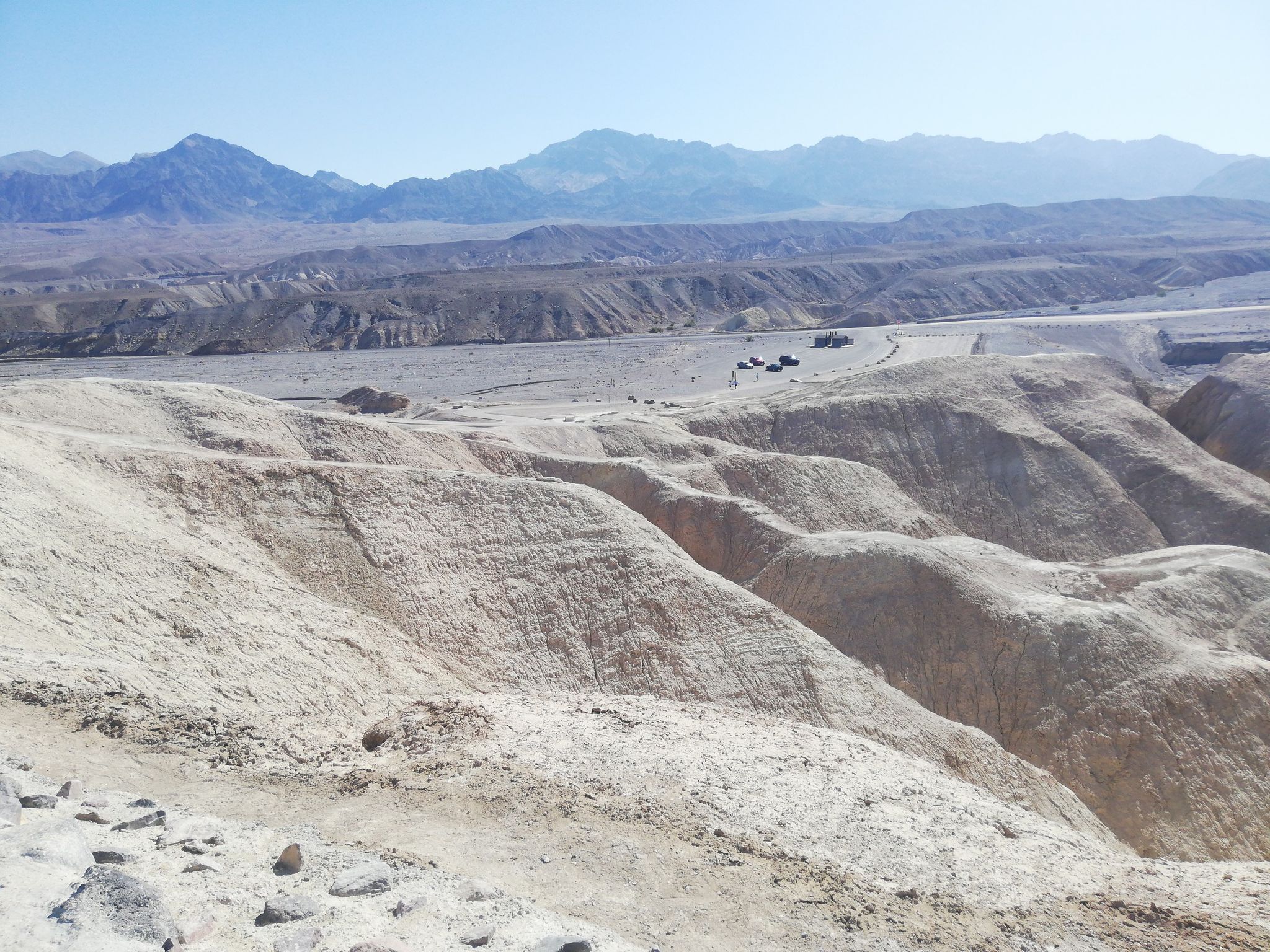 Rolling light-colored desert hills under a clear sky, distant mountains. - Badlands Loop Trail