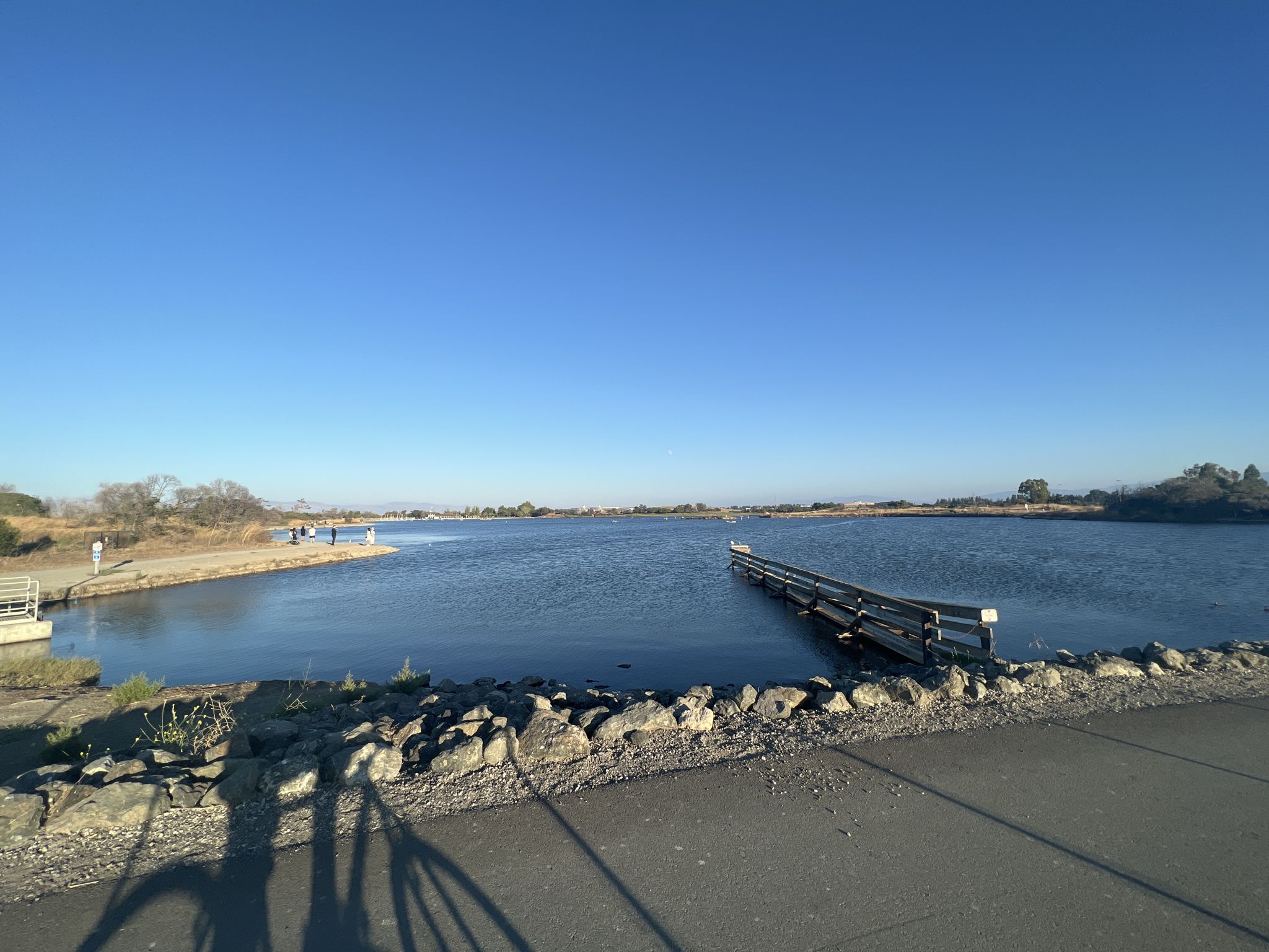 A long dock extends into a wide, calm lake under a bright blue sky. - Shoreline Lake – San Francisco Bay Trail loop from Computer History Museum